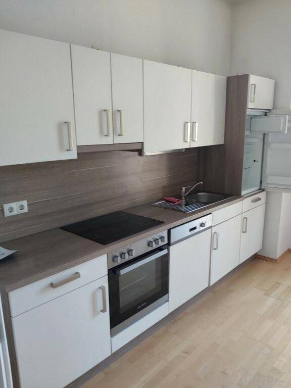 Moderne Einbauküche mit weißen Schränken, Holzoptik-Arbeitsplatte und integrierten Geräten.