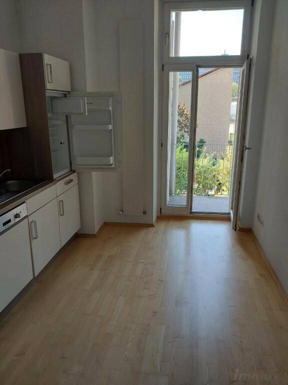 Heller Küchenbereich mit Holzfußboden und Zugang zu einem kleinen Balkon.