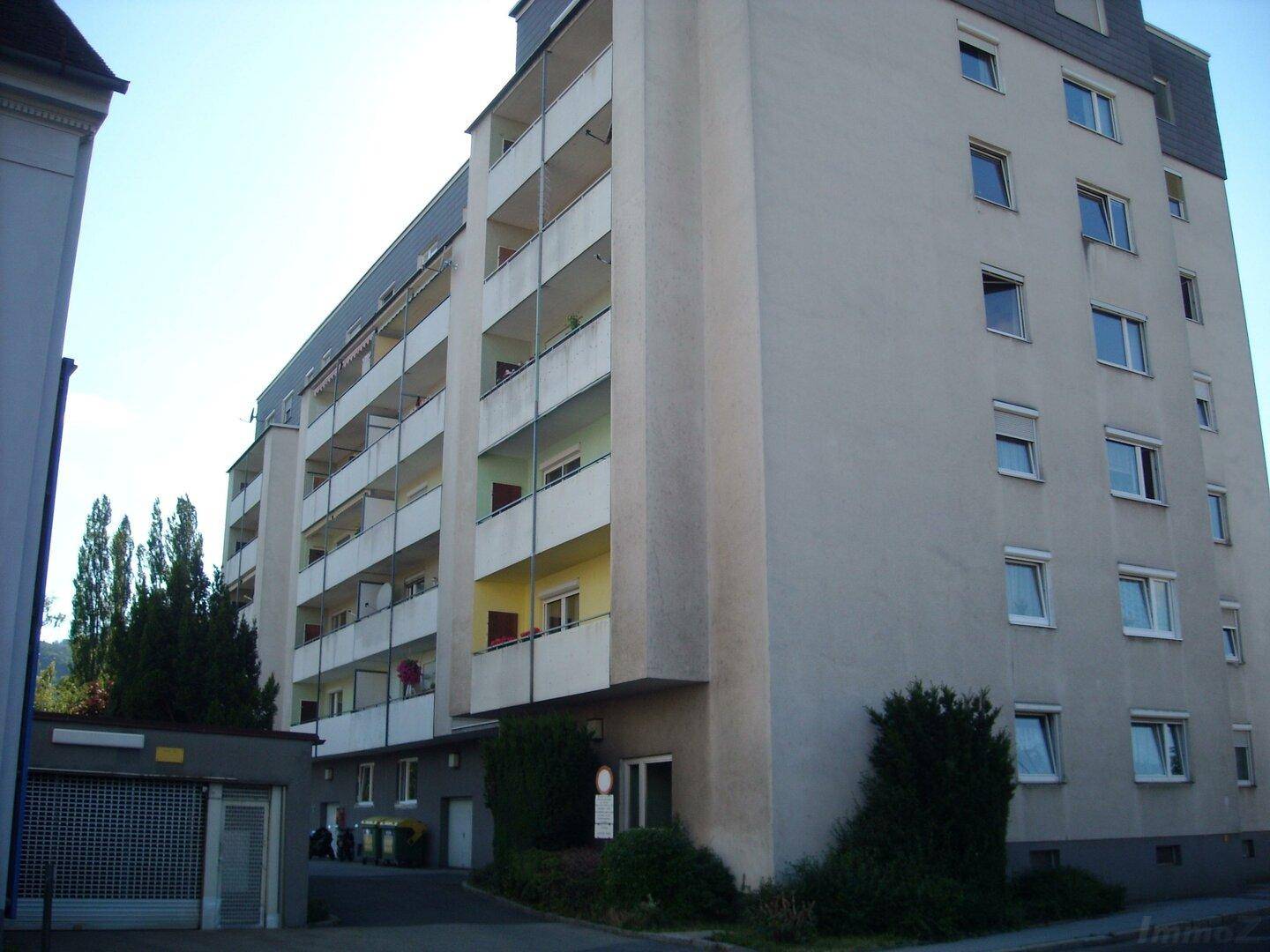 Mehrstöckiges Wohngebäude mit zahlreichen Balkonen, einer schlichten Fassade und Satteldach.