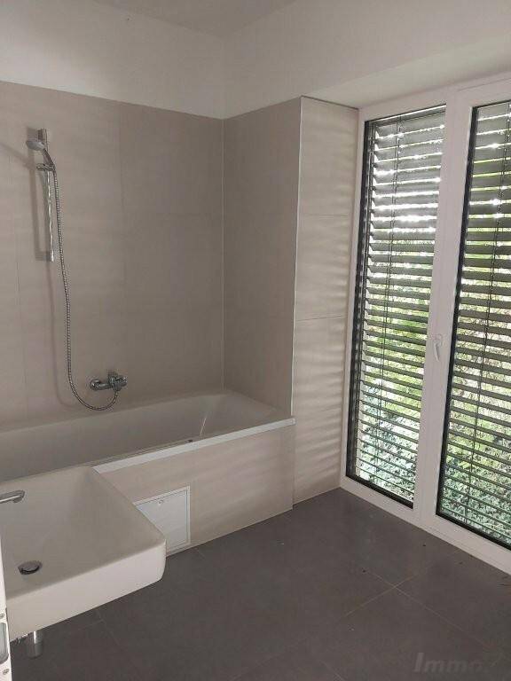 Modernes Badezimmer mit Badewanne, Waschbecken und großem Fenster für viel natürliches Tageslicht.