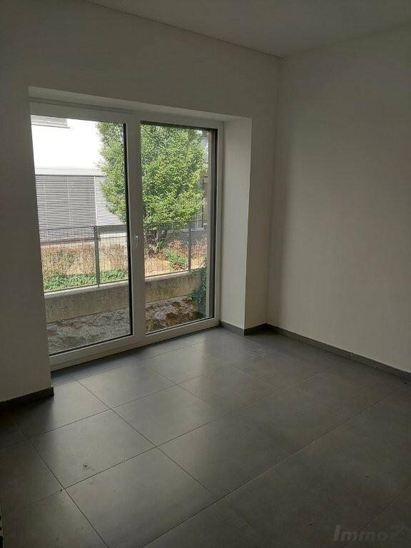 Ein helles Zimmer mit Fliesenboden und großem Fenster, das einen angenehmen Blick ins Grüne bietet.