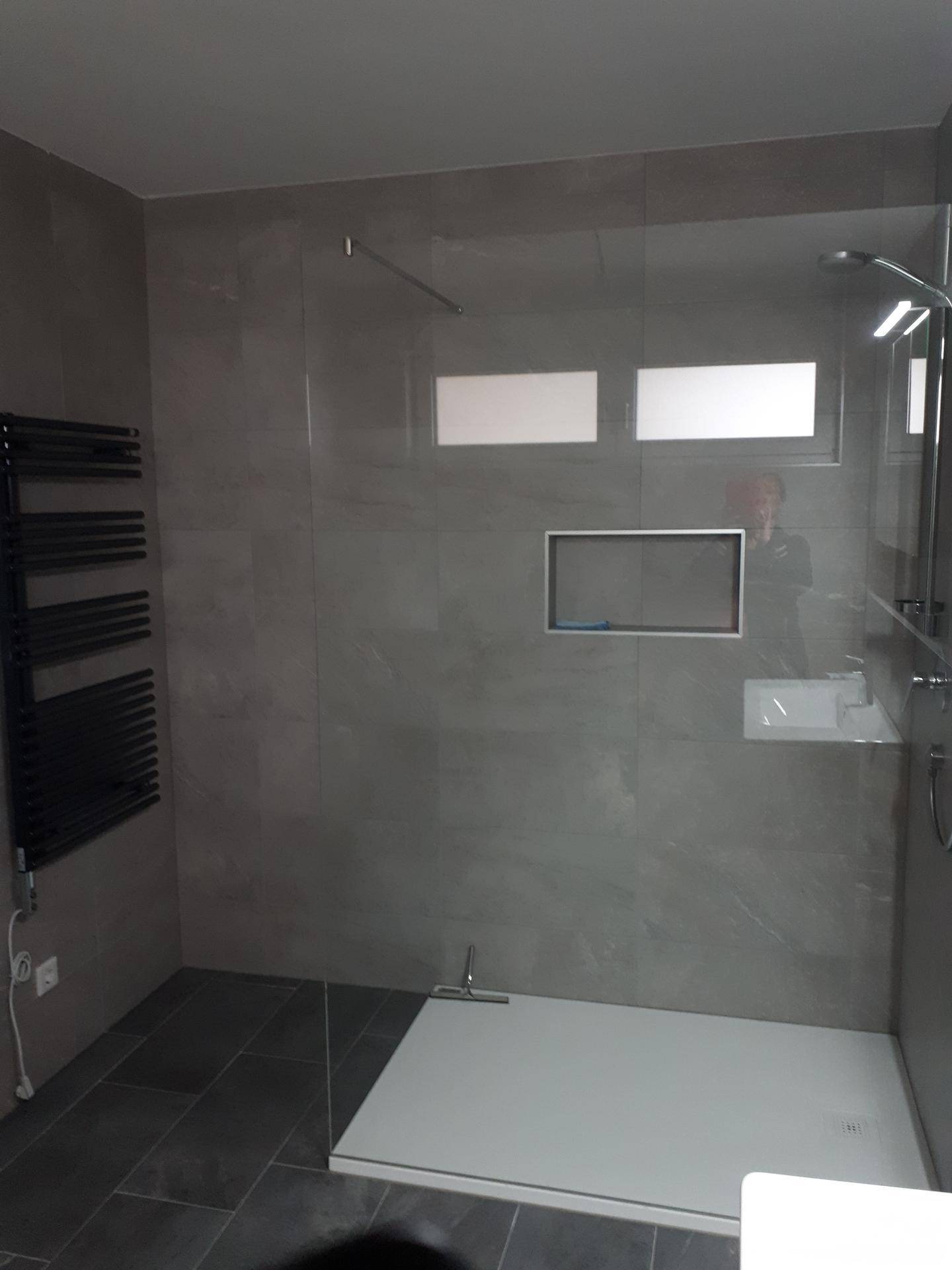 Zeitgemäßes Badezimmer mit großzügiger begehbarer Dusche, grauen Fliesen und beheiztem Handtuchhalter.
