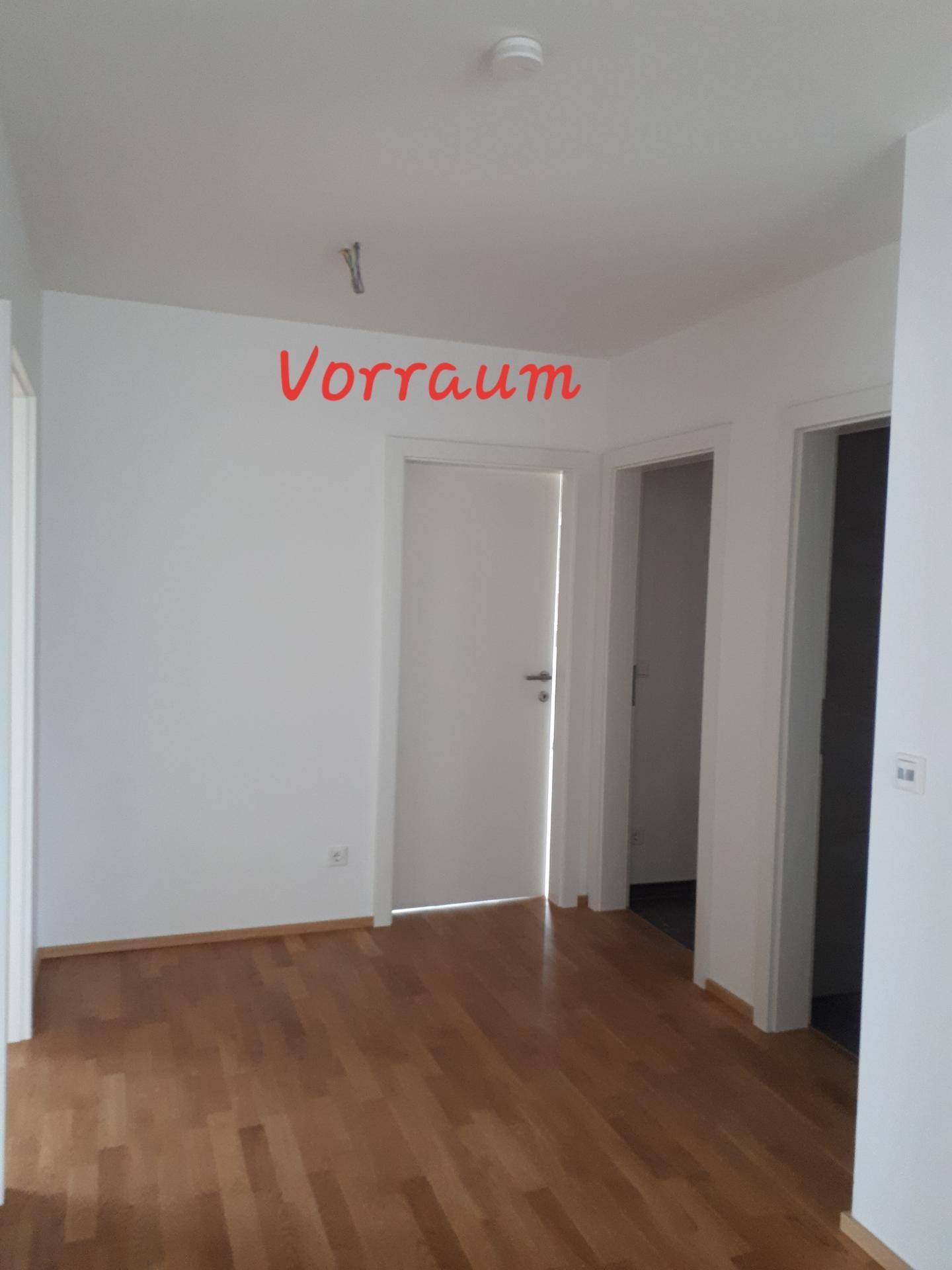 Freundlicher Vorraum mit Holzfußboden und weißen Wänden, der Zugang zu angrenzenden Zimmern bietet.