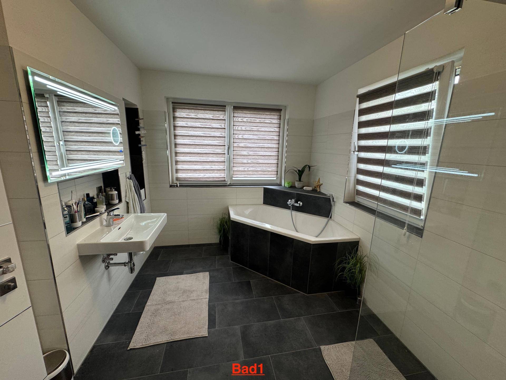 Modernes Badezimmer mit Eckbadewanne, Waschtisch und großformatigen Fliesen.