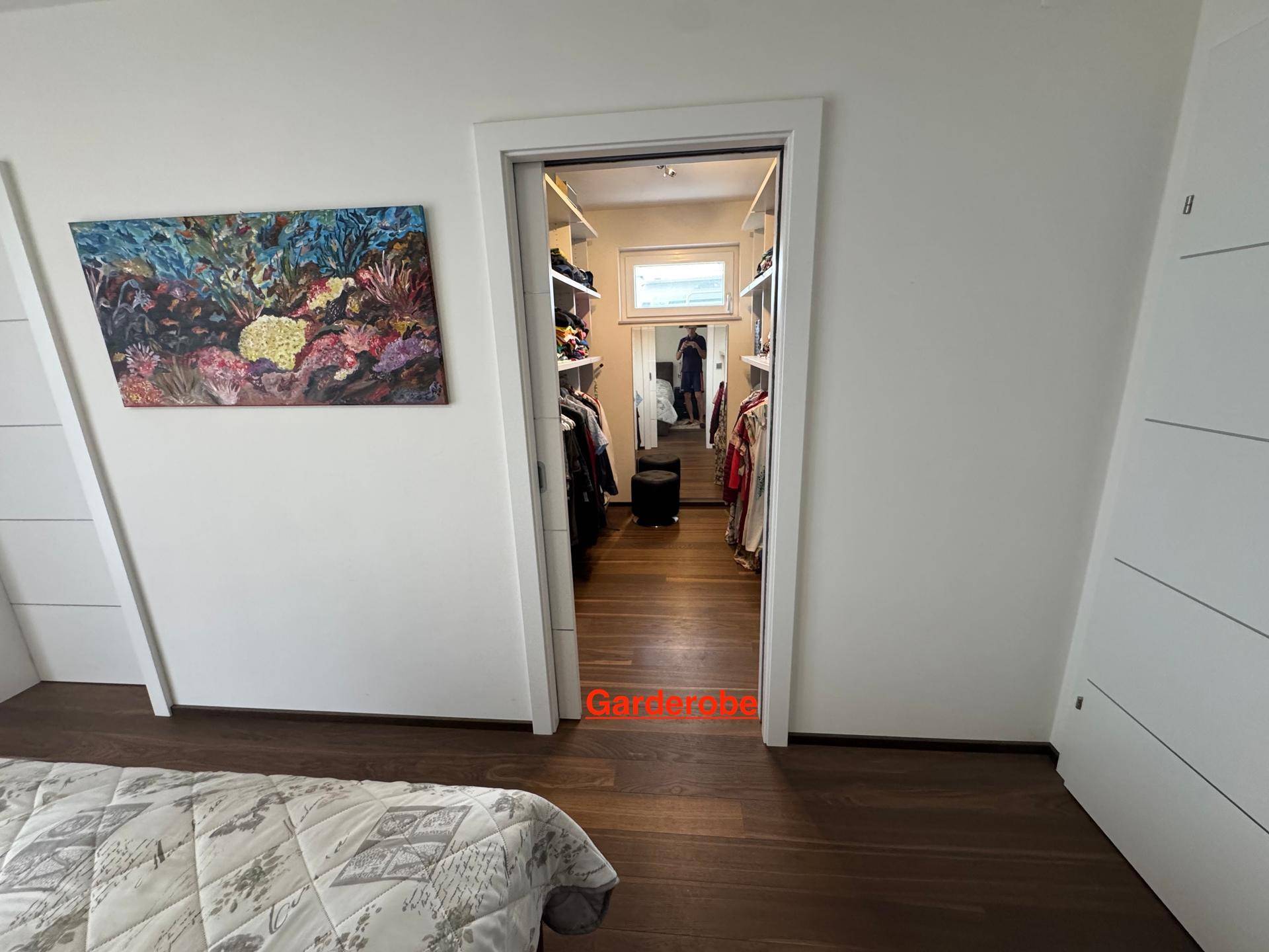 Schlafzimmer mit Holzboden und Zugang zu einem begehbaren Kleiderschrank.