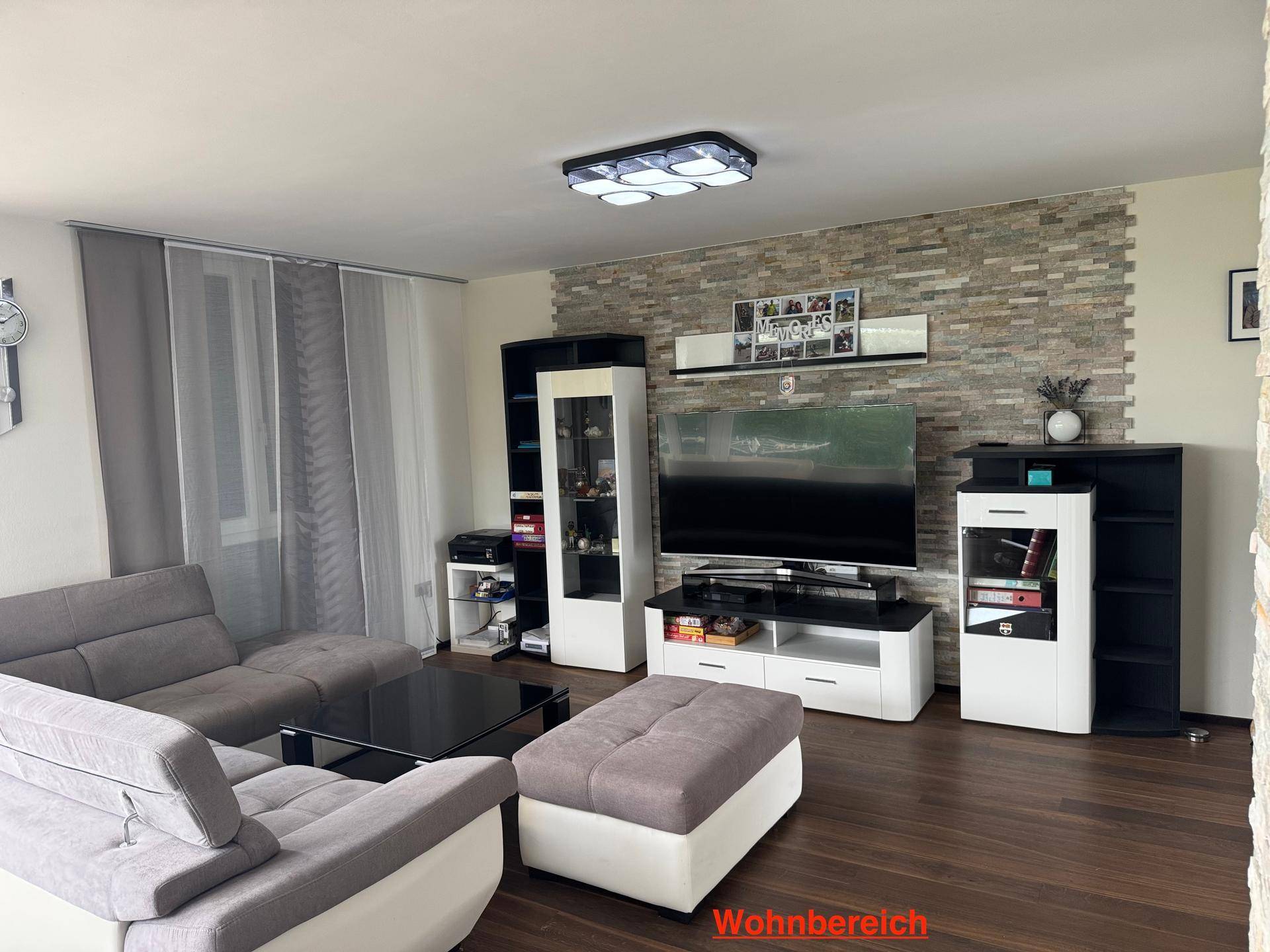Gemütlicher Wohnbereich mit Holzboden, großer Couch und einer dekorativen Steinwand hinter dem Fernseher.