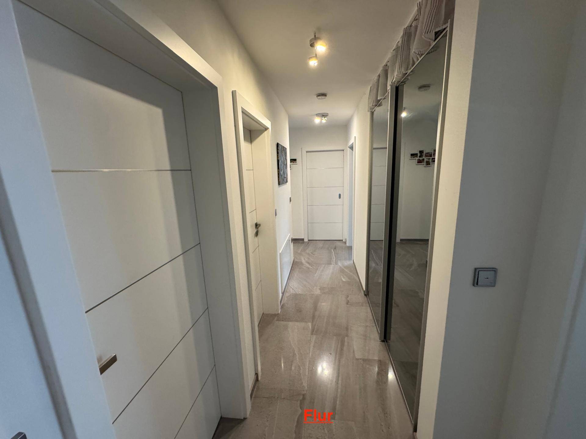 Heller Flur mit modernen Fliesen und einem großen Spiegelschrank.