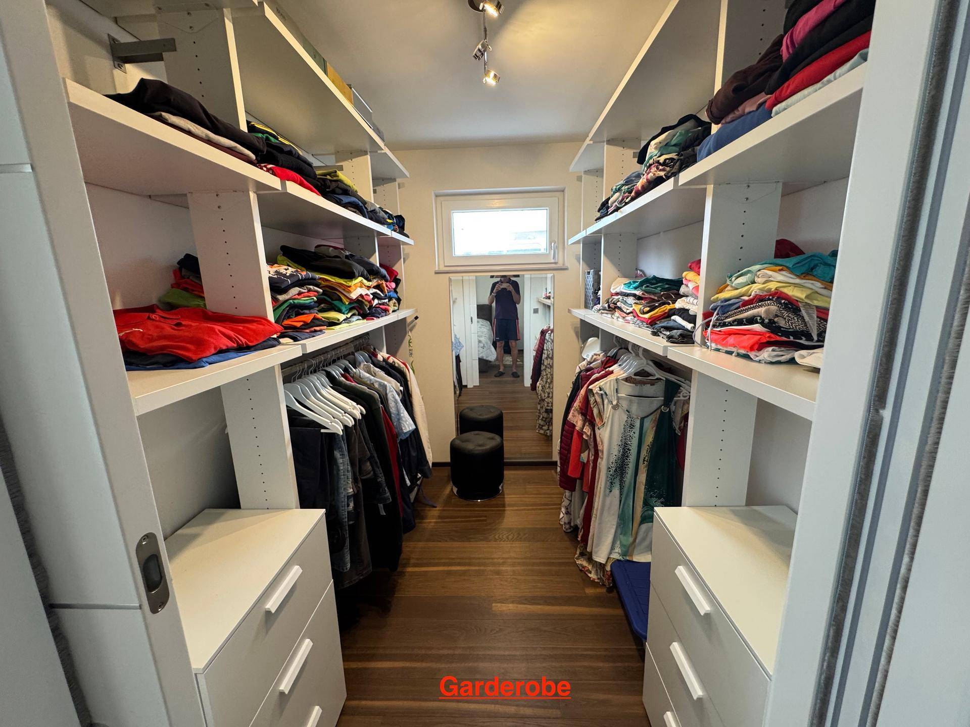 Begehbarer Kleiderschrank mit Regalen, Schubladen und einem Fenster für Tageslicht.