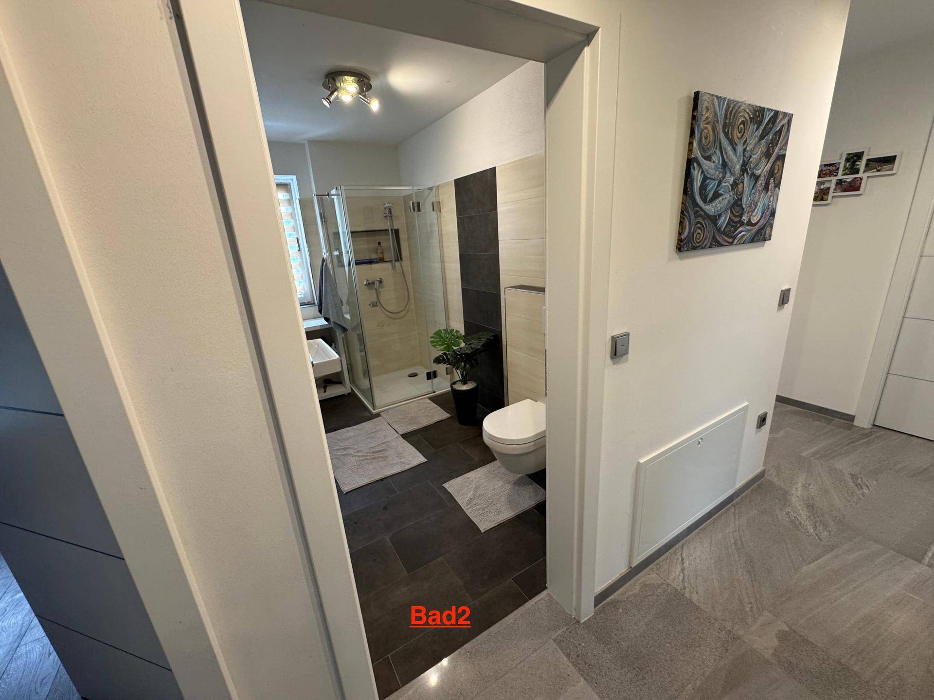 Modernes Badezimmer mit ebenerdiger Dusche und dunklen Bodenfliesen.