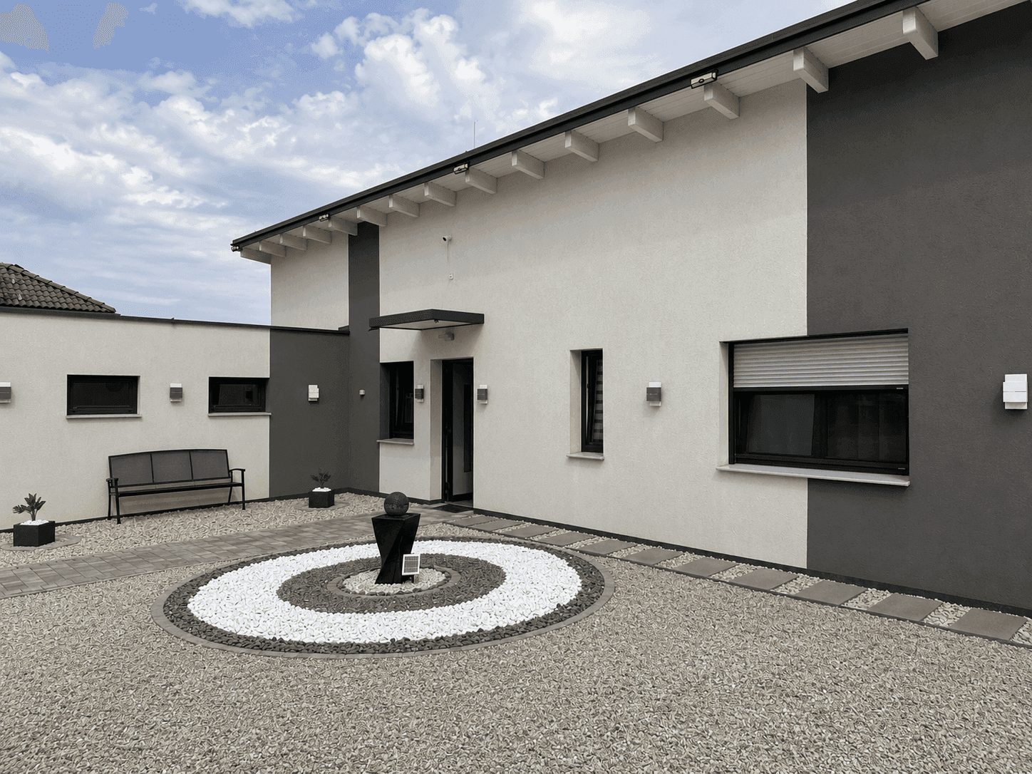 Moderne Hausfassade in Weiß und Grau mit stilvollem Eingangsbereich und Zierbrunnen.