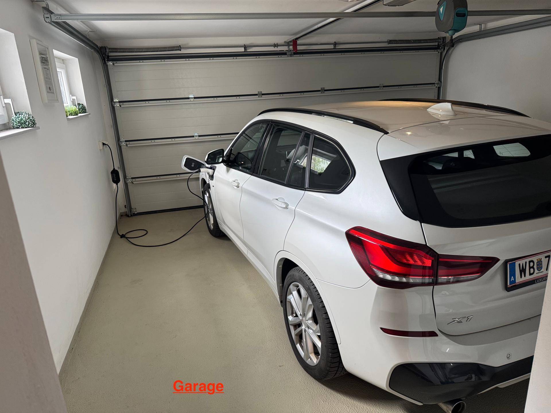 Saubere Garage mit einem weißen SUV und einer Ladestation für Elektrofahrzeuge.