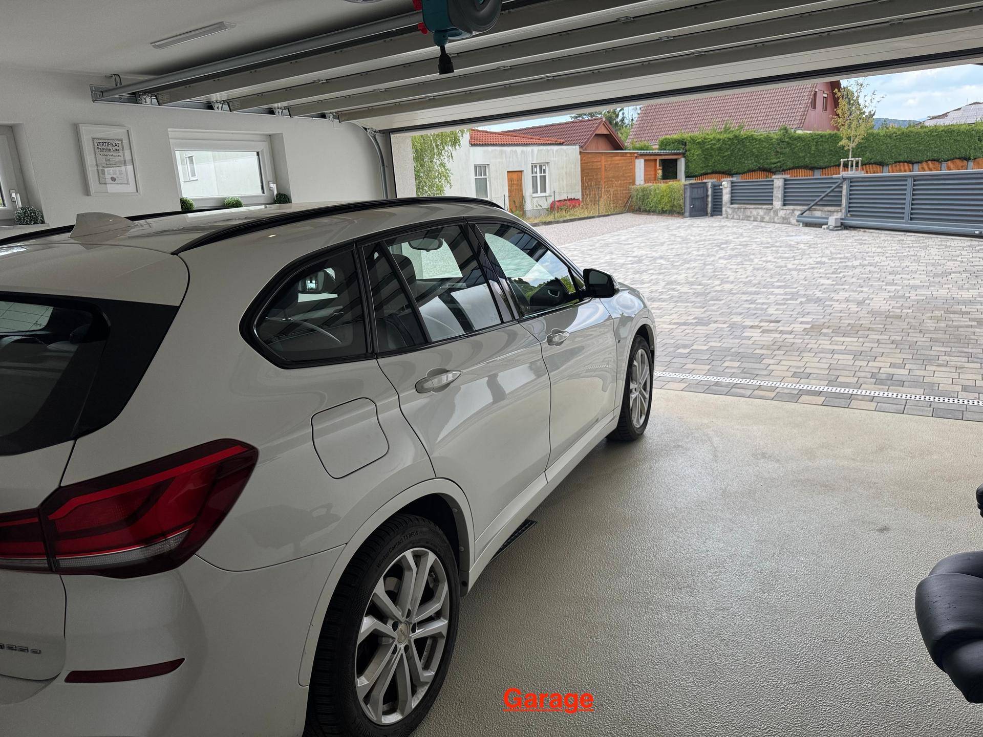 Garage mit geparktem Auto und Blick auf die gepflasterte Einfahrt.