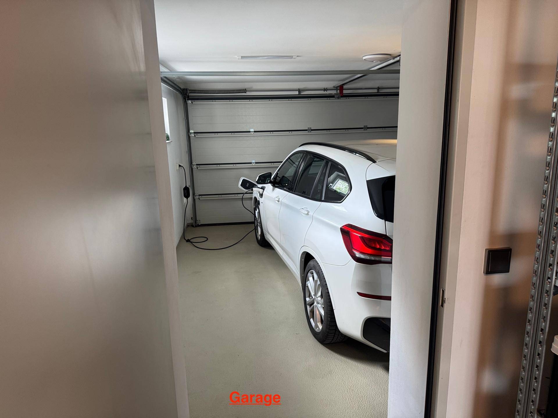 Moderne Garage mit einem geparkten Elektrofahrzeug und Ladestation.