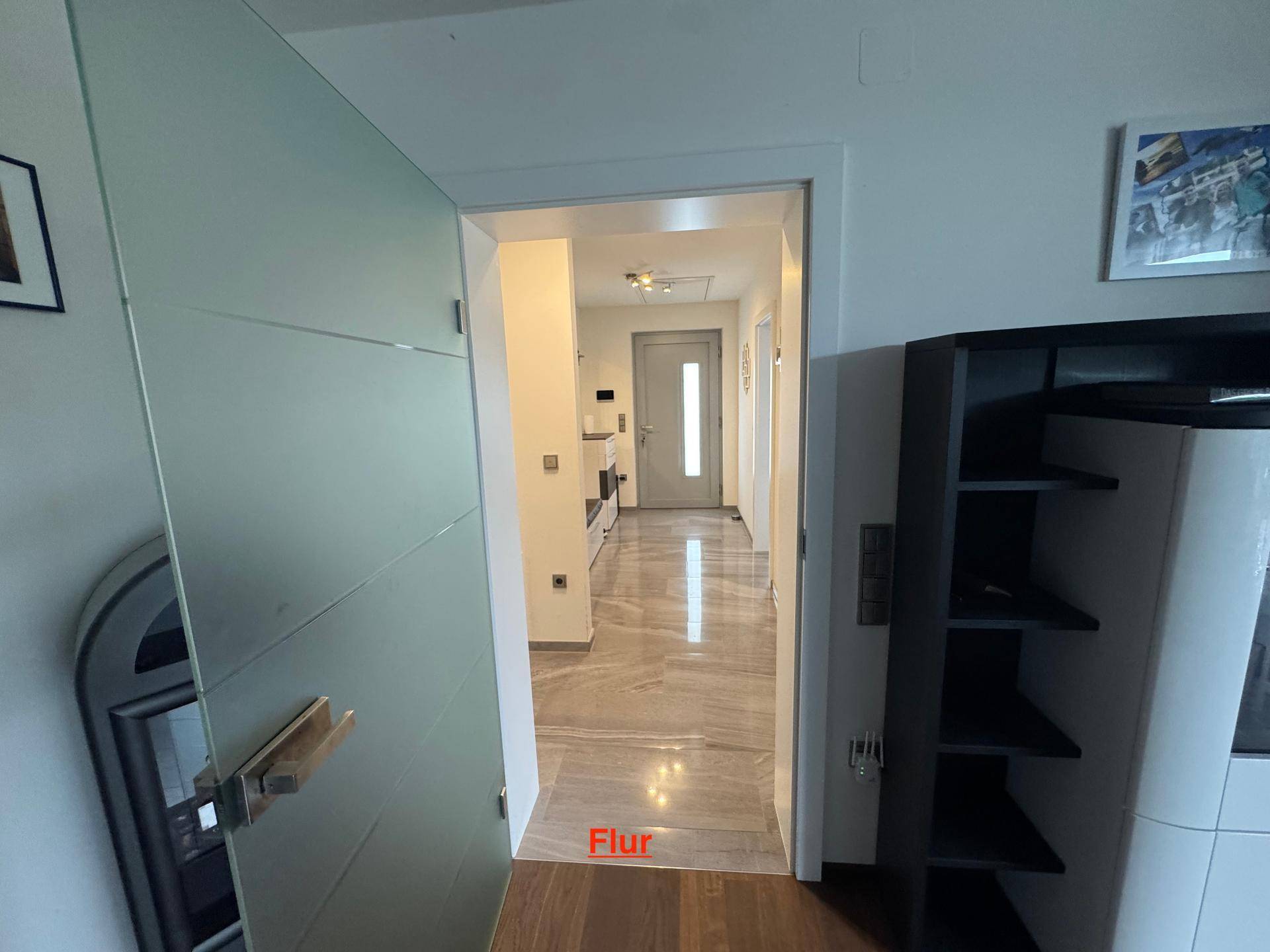 Heller Flur mit modernen Fliesen und einem Durchgang zu weiteren Räumen des Hauses.