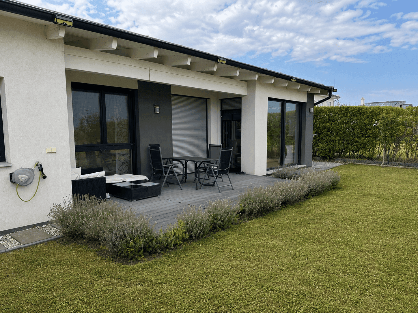 Moderne Terrasse mit Gartenmöbeln und direktem Zugang zum gepflegten Rasenbereich des Gartens.