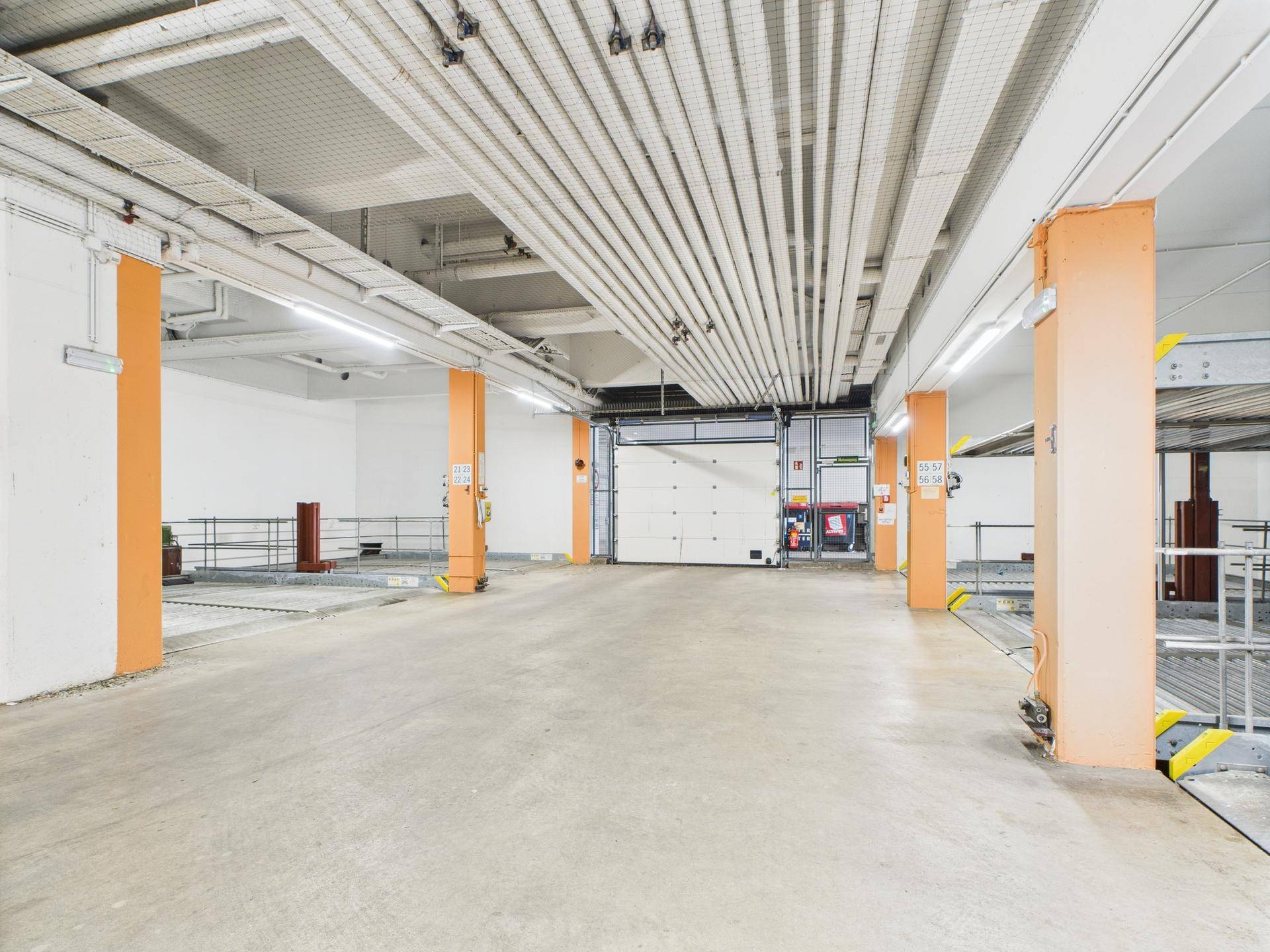 Heller Tiefgaragenbereich mit Rolltor und Zugang zu den Parkplätzen und Fahrradabstellplätzen.