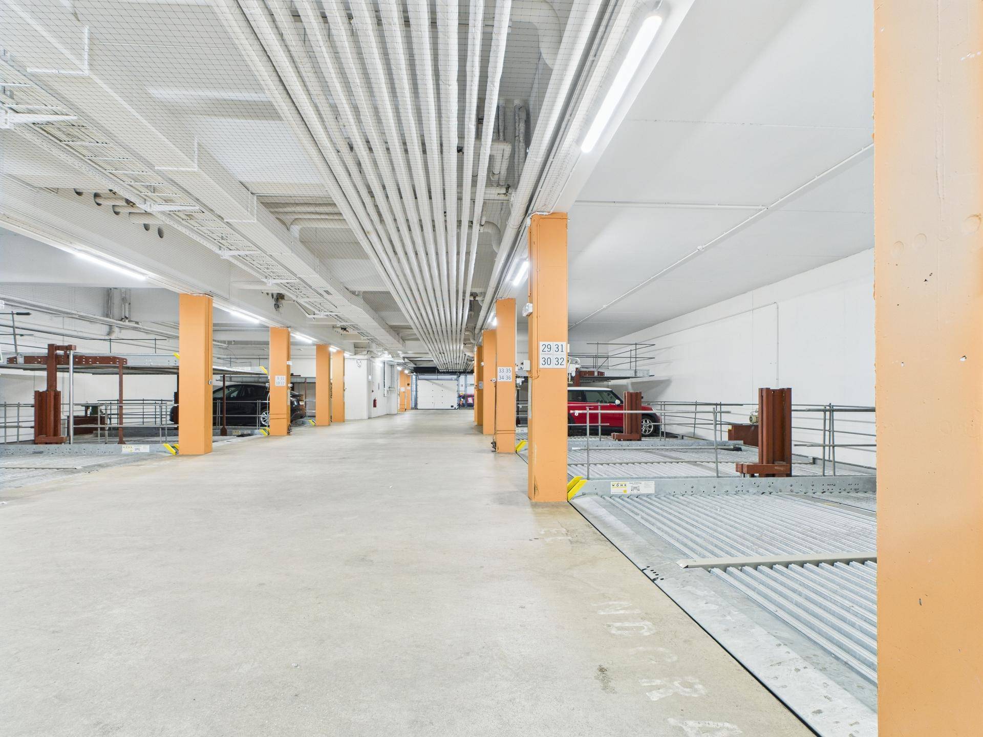Lange Reihe von Doppelparker-Systemen in der gut beleuchteten Tiefgarage des Gebäudes.
