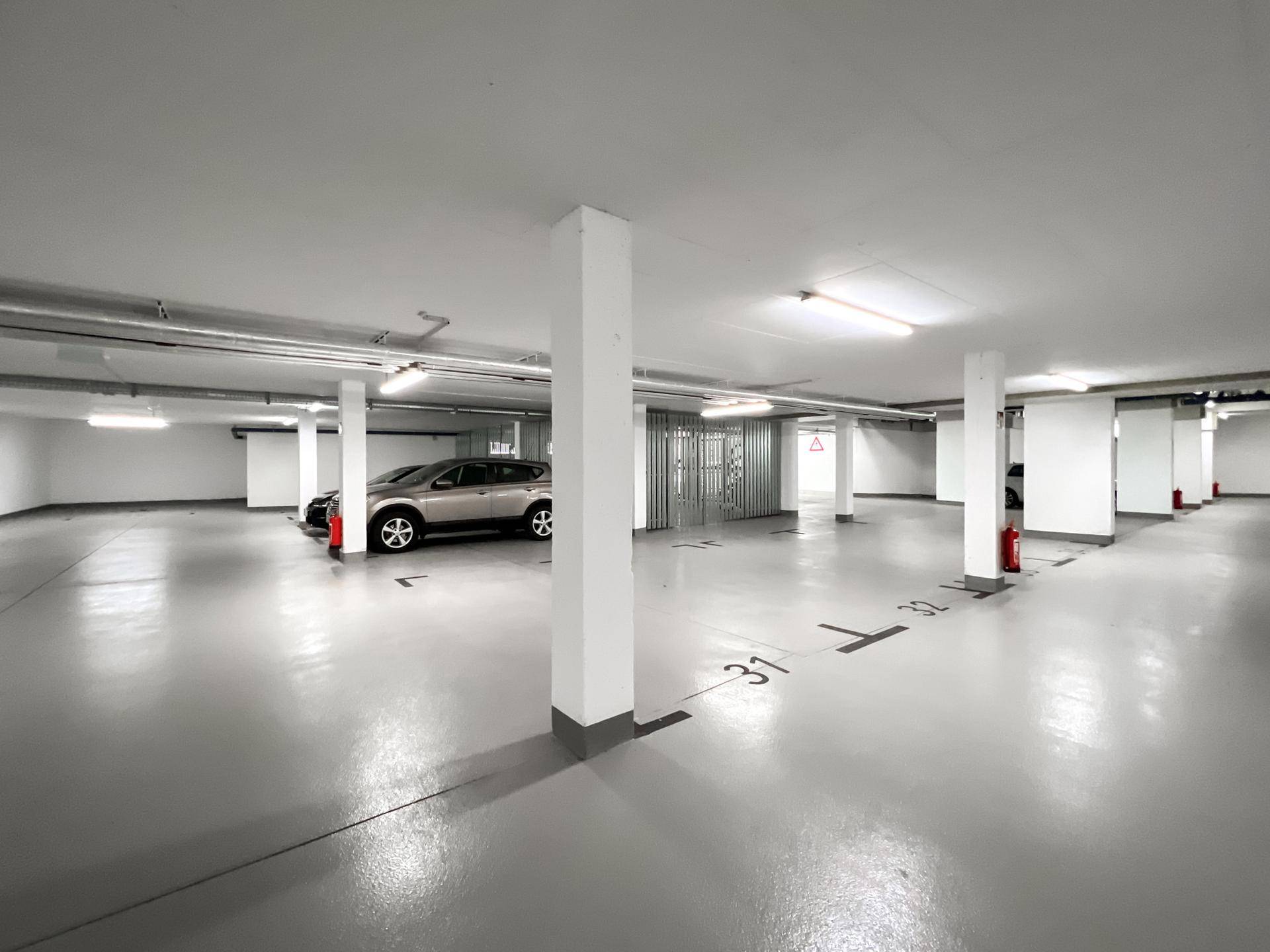 Moderne Tiefgarage mit nummerierten Stellplätzen und glattem Betonboden, gut beleuchtet.