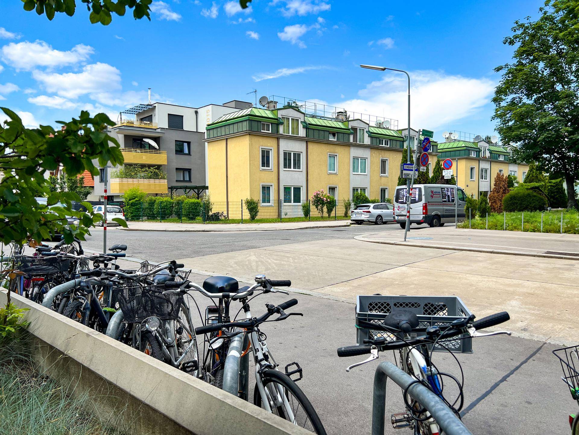 Wohngebäude in einer städtischen Umgebung mit Fahrrädern im Vordergrund und blauem Himmel.
