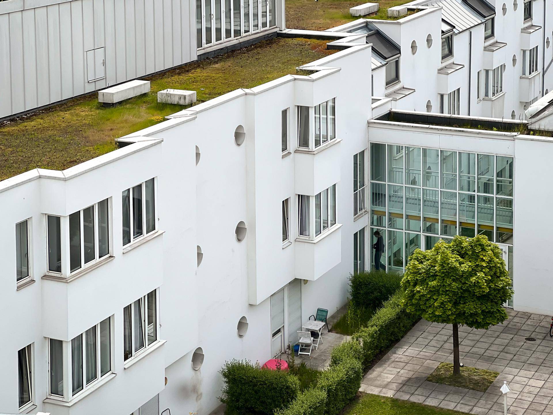 Vogelperspektive auf moderne Wohngebäude mit begrünten Dächern und Innenhof.