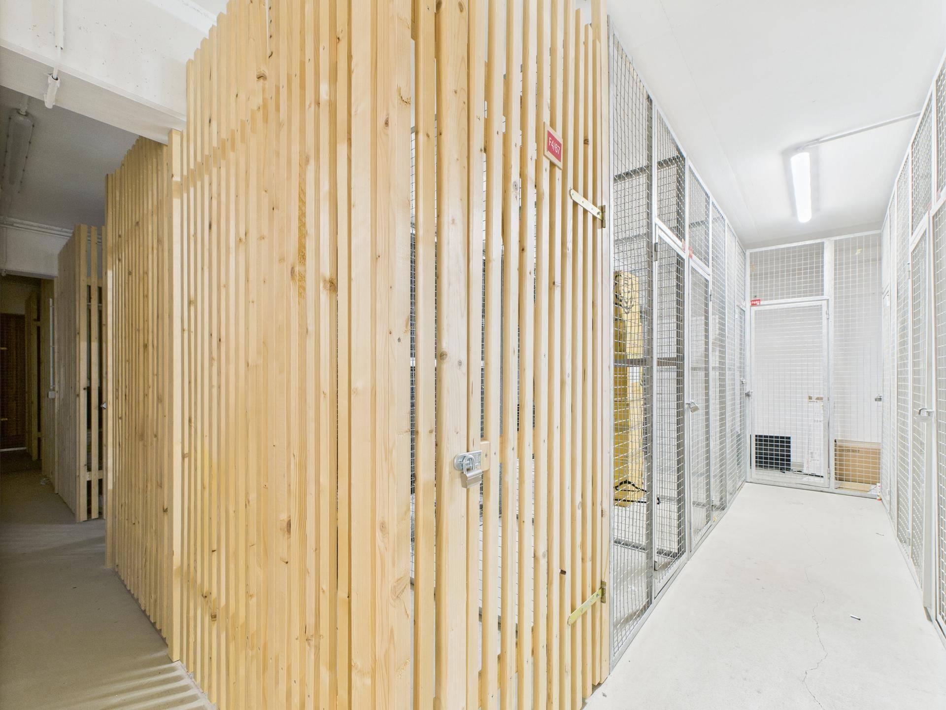 Kellerabteile mit Holz- und Gitterwänden für zusätzlichen Stauraum.