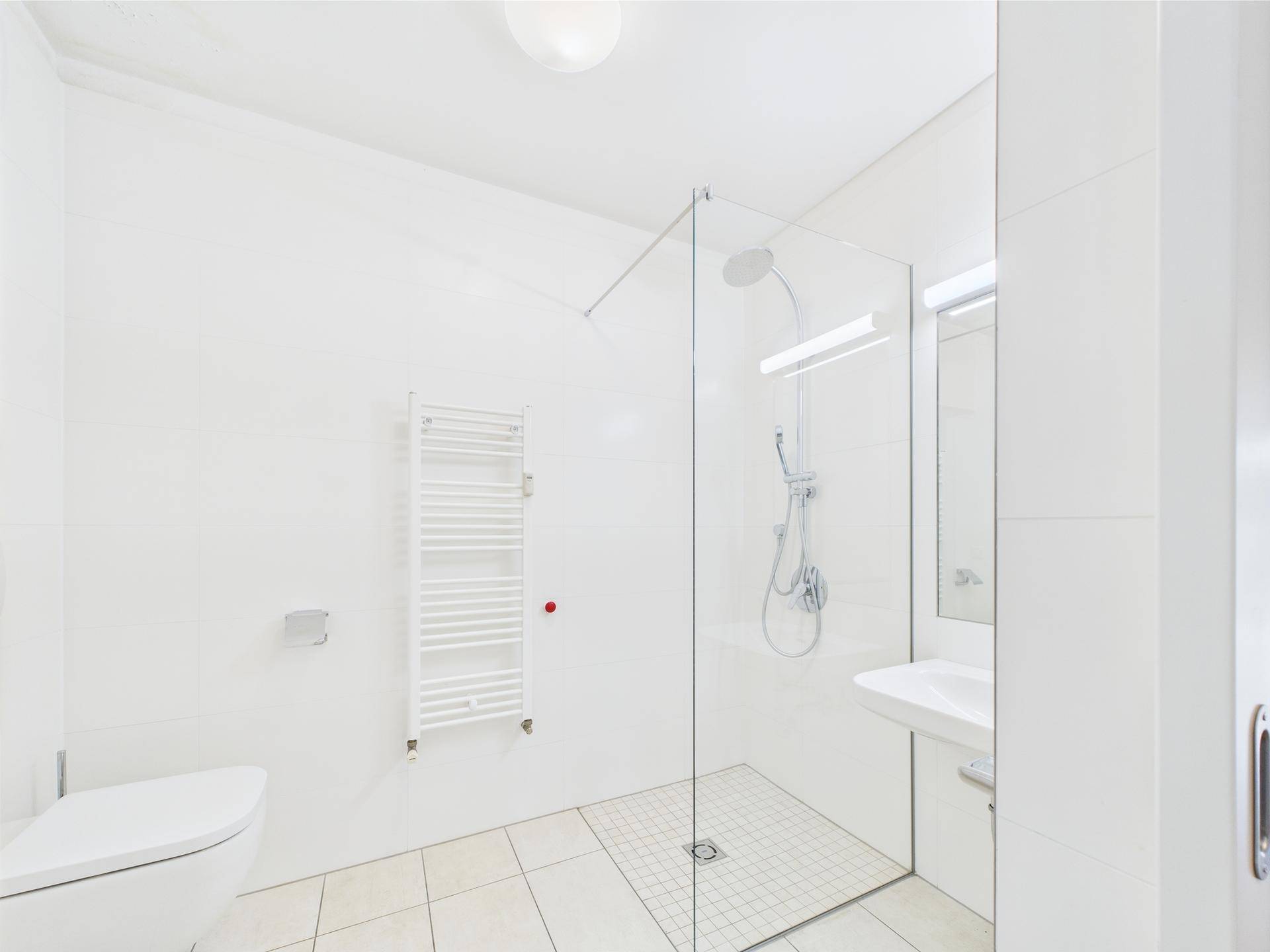 Modernes Badezimmer mit ebenerdiger Dusche, Wand-WC und beheiztem Handtuchhalter.