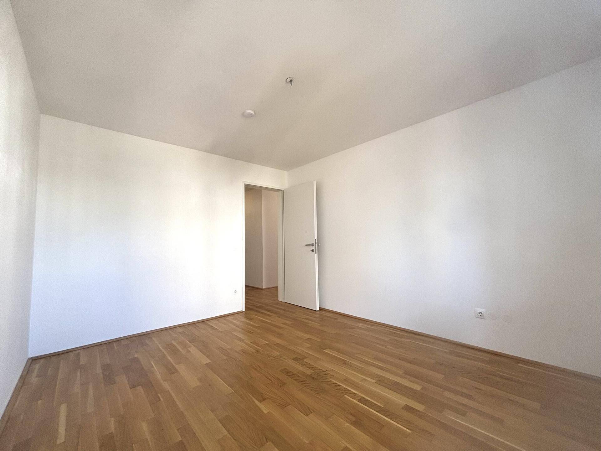 Geräumiges Zimmer mit hellem Parkettboden und weiß gestrichenen Wänden, ideal als Schlaf- oder Arbeitszimmer.