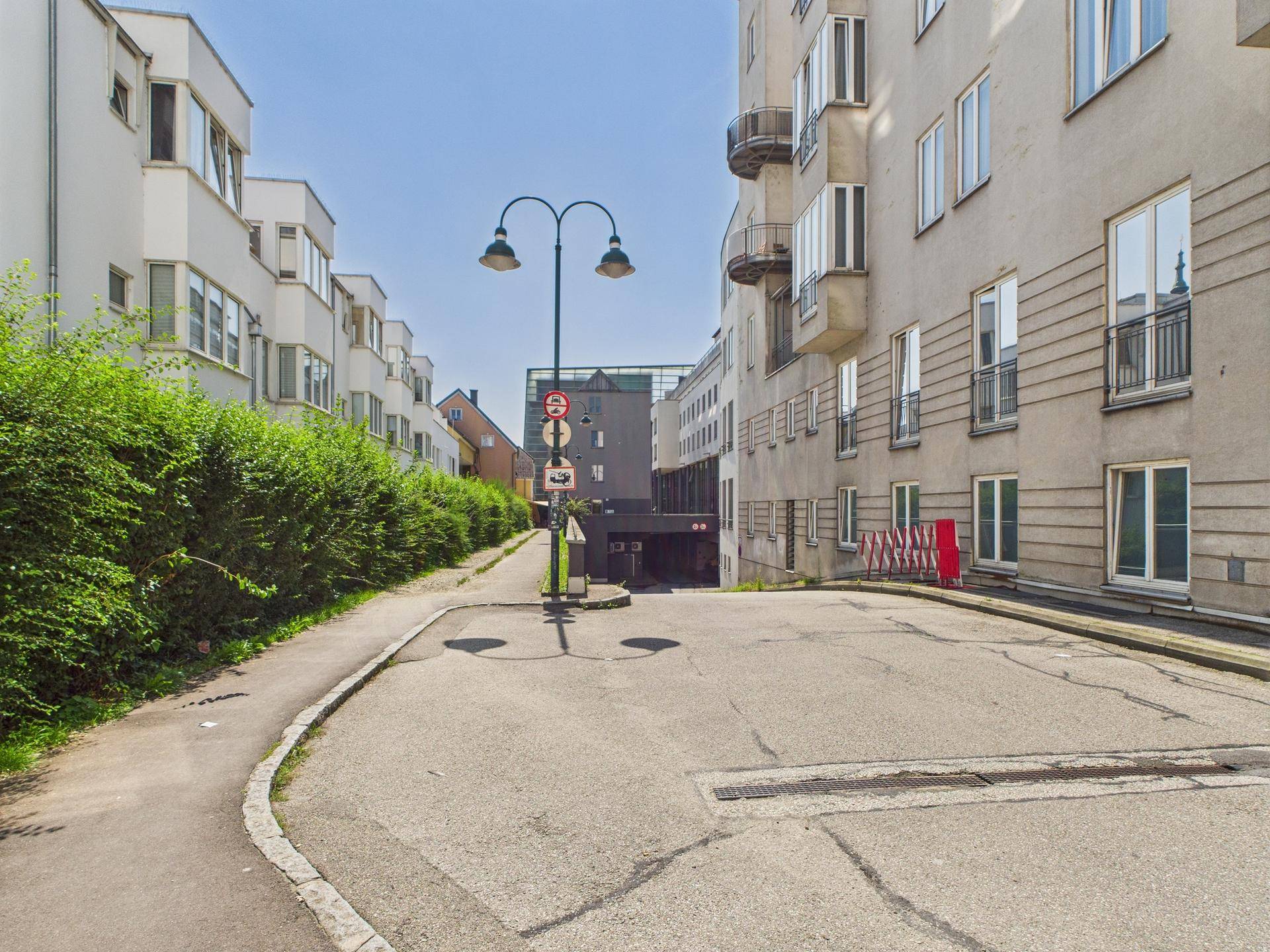 Zufahrt zu einer Tiefgarage von der Straße aus, umgeben von Wohngebäuden.