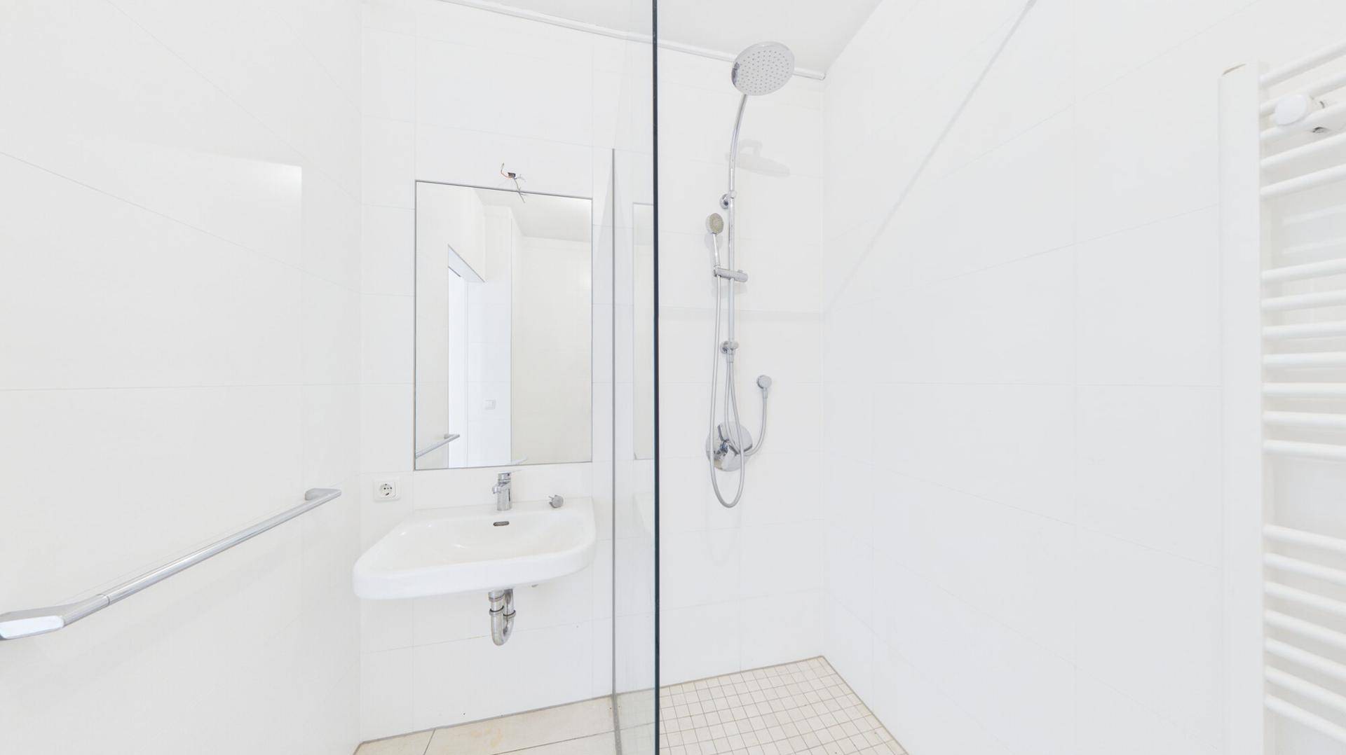 Modernes Badezimmer mit ebenerdiger Dusche, Einzelwaschbecken und beheiztem Handtuchhalter.
