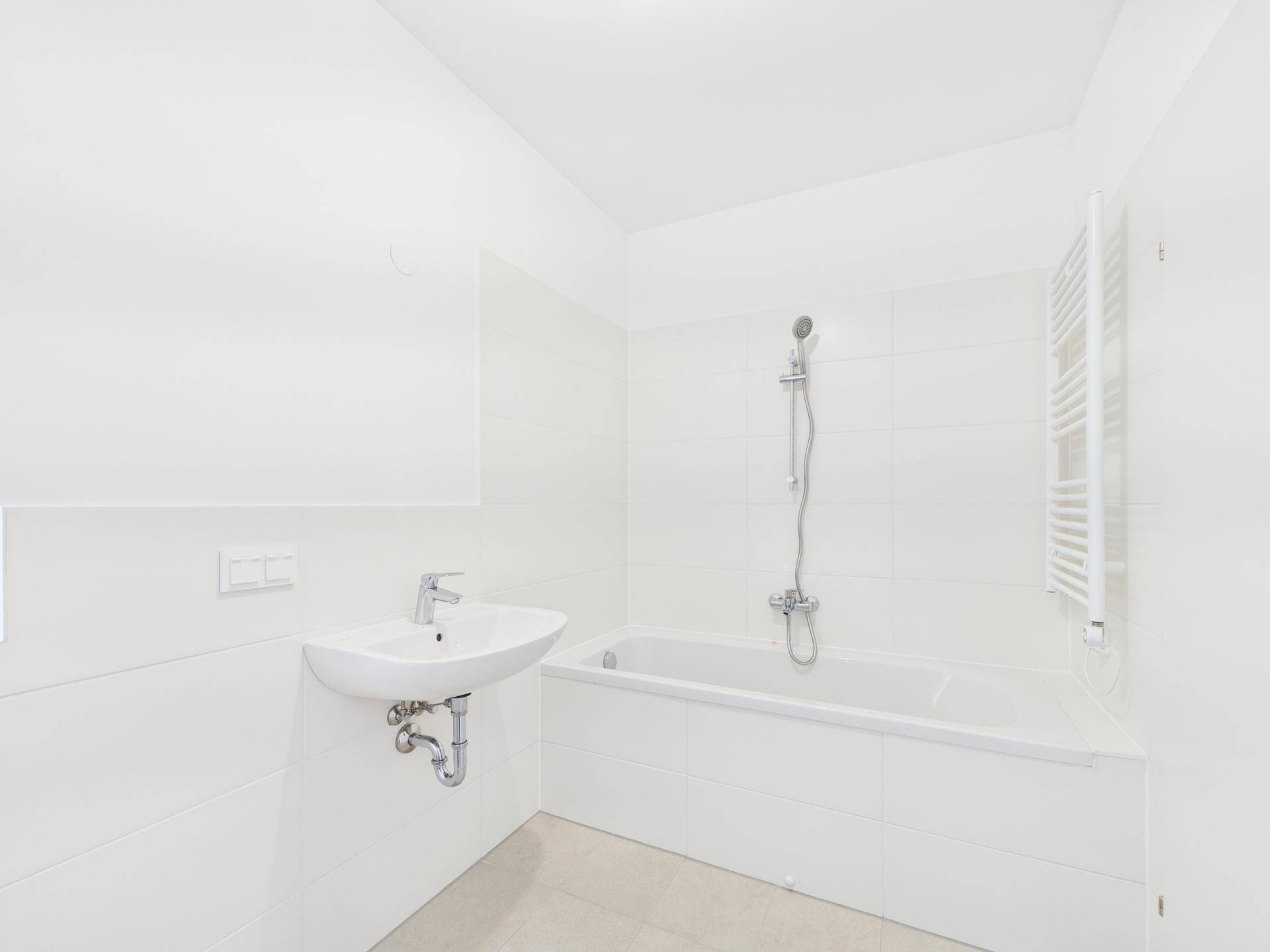 Modernes Badezimmer mit weiß gefliesten Wänden, Badewanne, Waschbecken und beheiztem Handtuchhalter.
