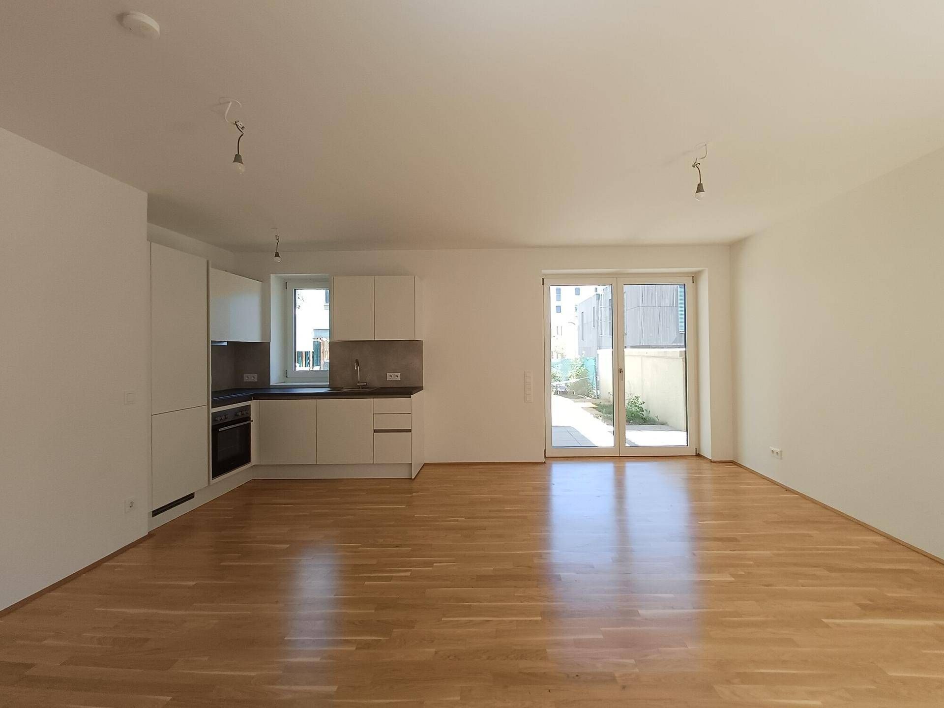 Heller offener Wohn-Essbereich mit integrierter Küche und Zugang zur Terrasse.