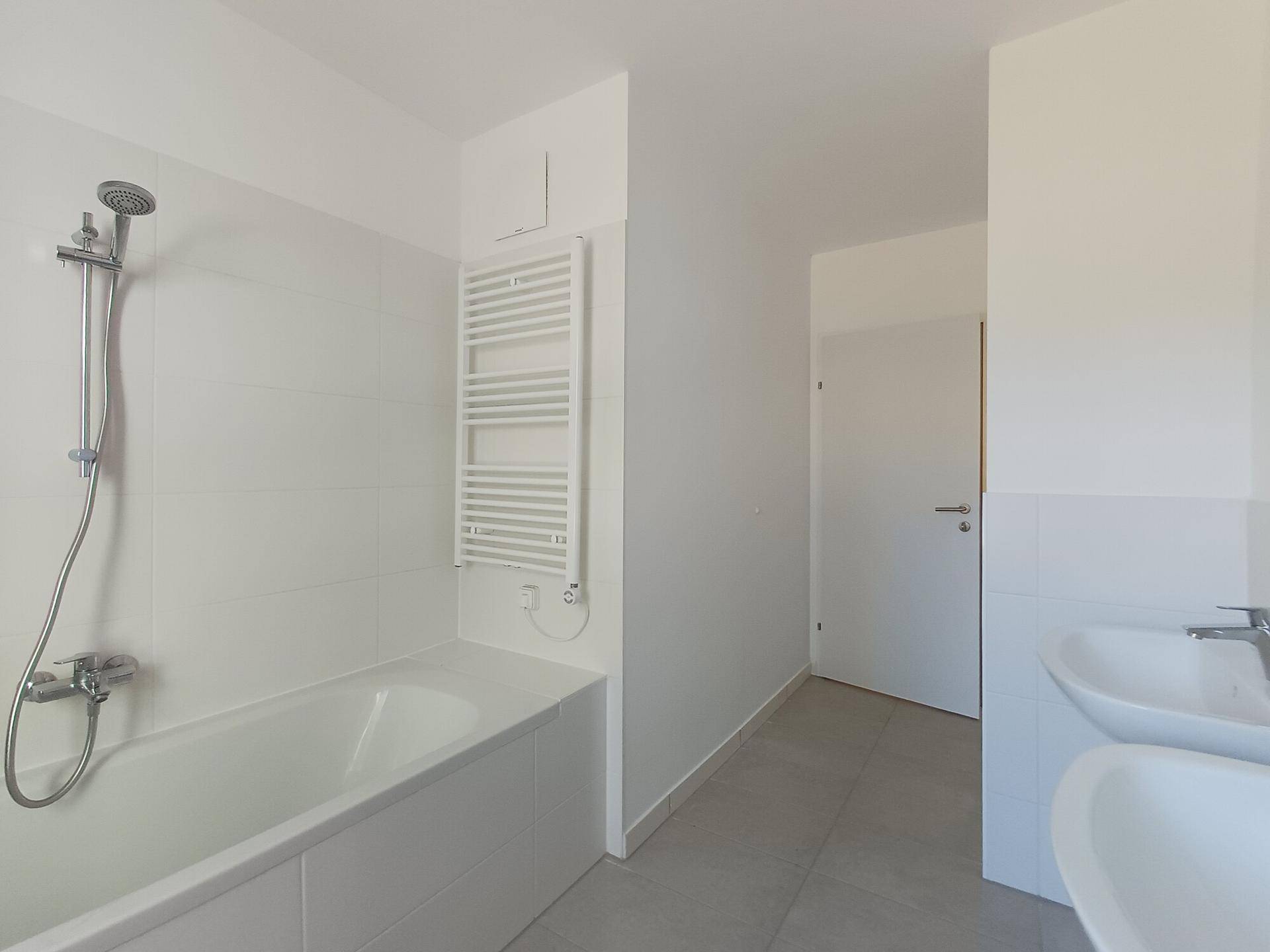 Helles Badezimmer mit Badewanne, Duscharmatur und beheiztem Handtuchhalter.