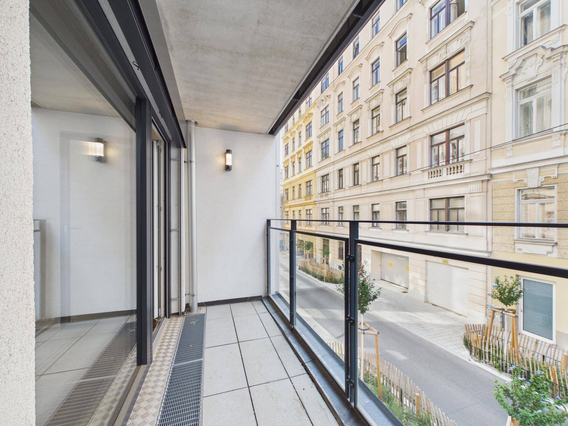 Geräumiger Balkon mit Fliesenboden und Blick auf die Straße und gegenüberliegende Gebäude.