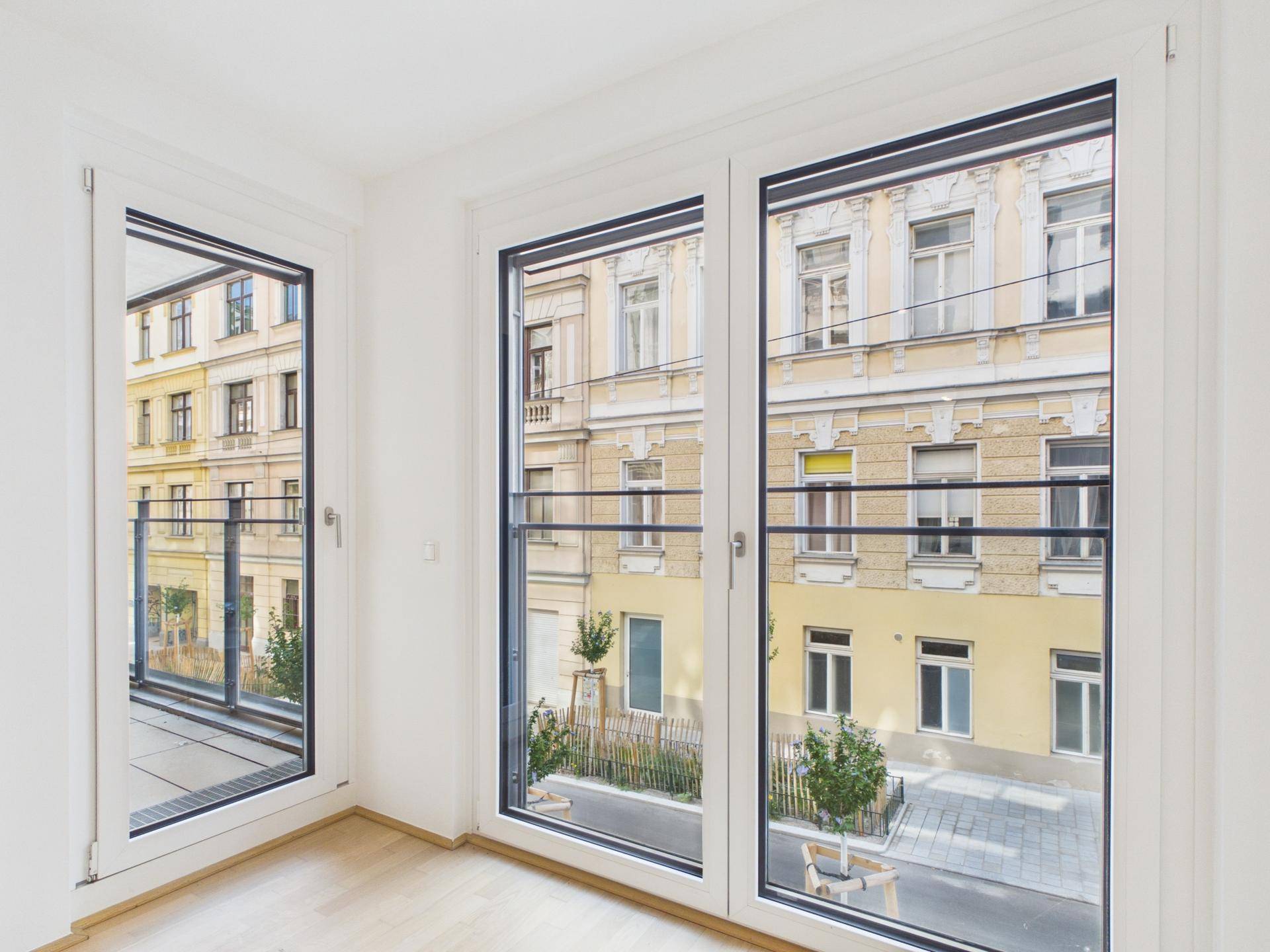 Heller Raum mit großen Fenstern, die einen Blick auf die Straße und die umliegenden Gebäude bieten.