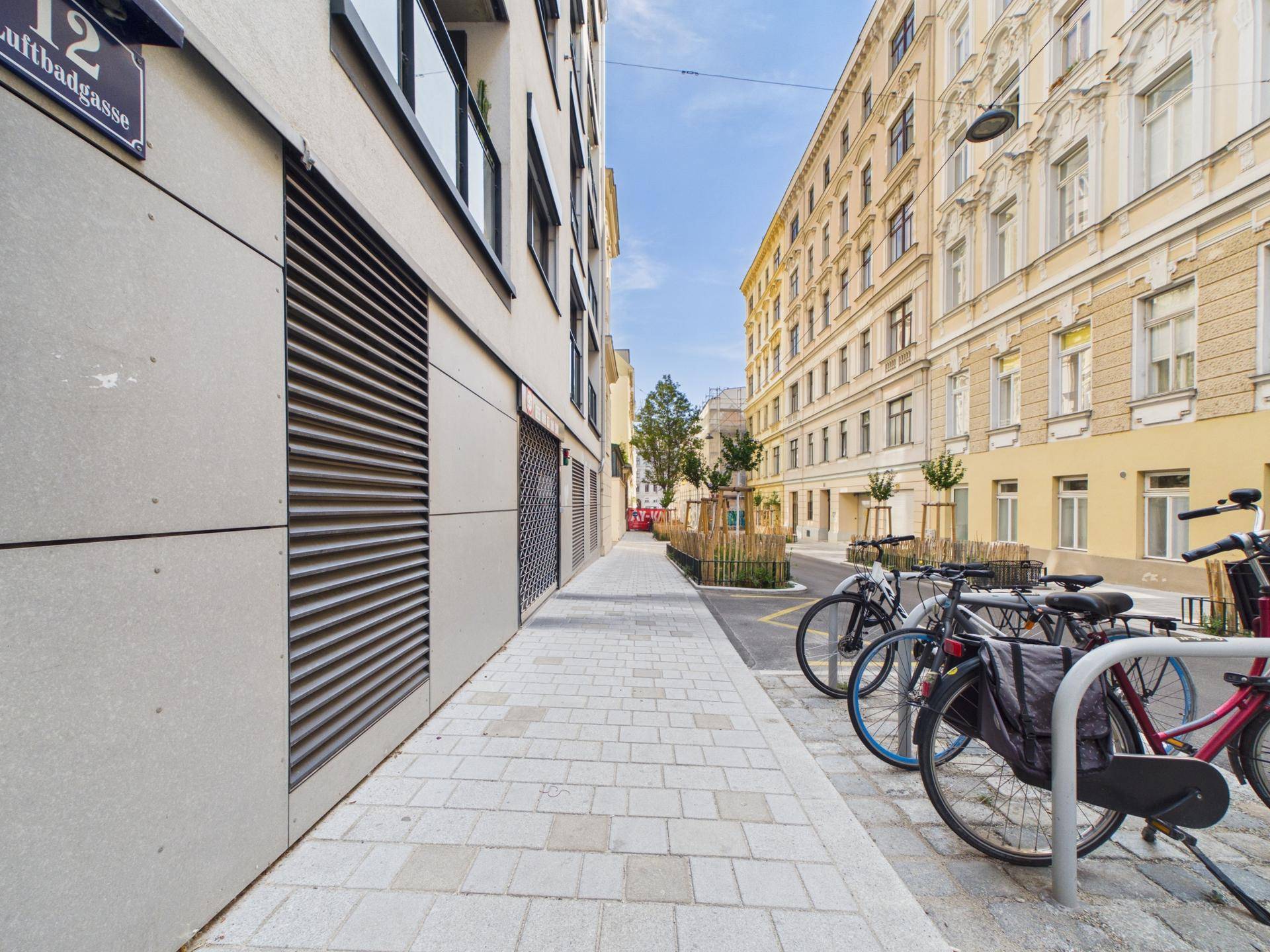 Moderne Straßenansicht mit Fahrradständern und einem neuen Gebäude neben älteren Fassaden.
