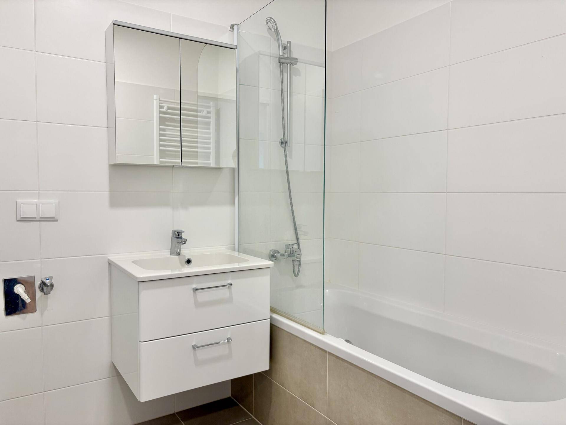 Modernes Badezimmer mit Badewanne, Glasduschwand, Waschtisch und Spiegelschrank.