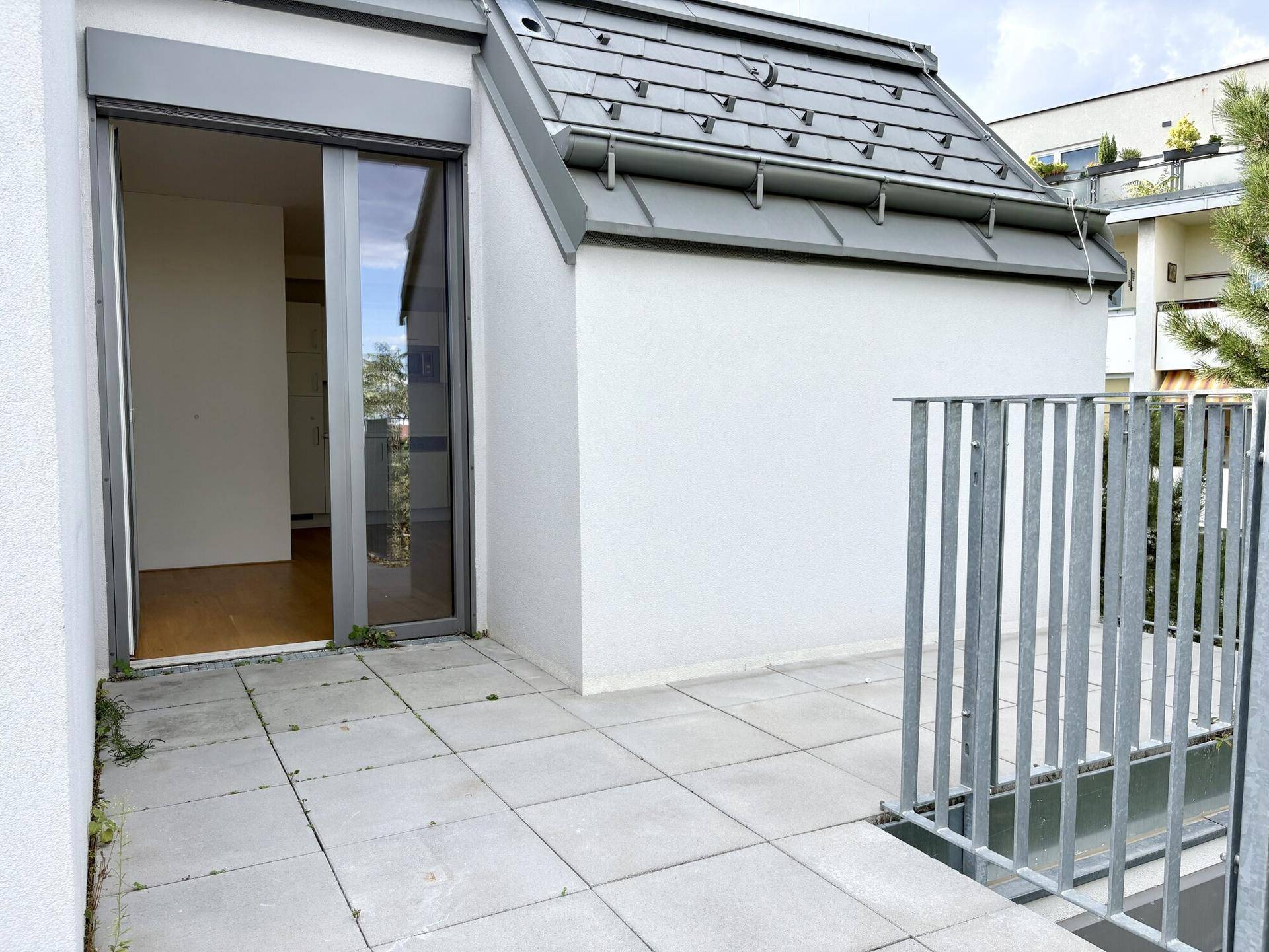 Terrasse mit Zugang zu einem Innenraum und Blick auf die Umgebung.