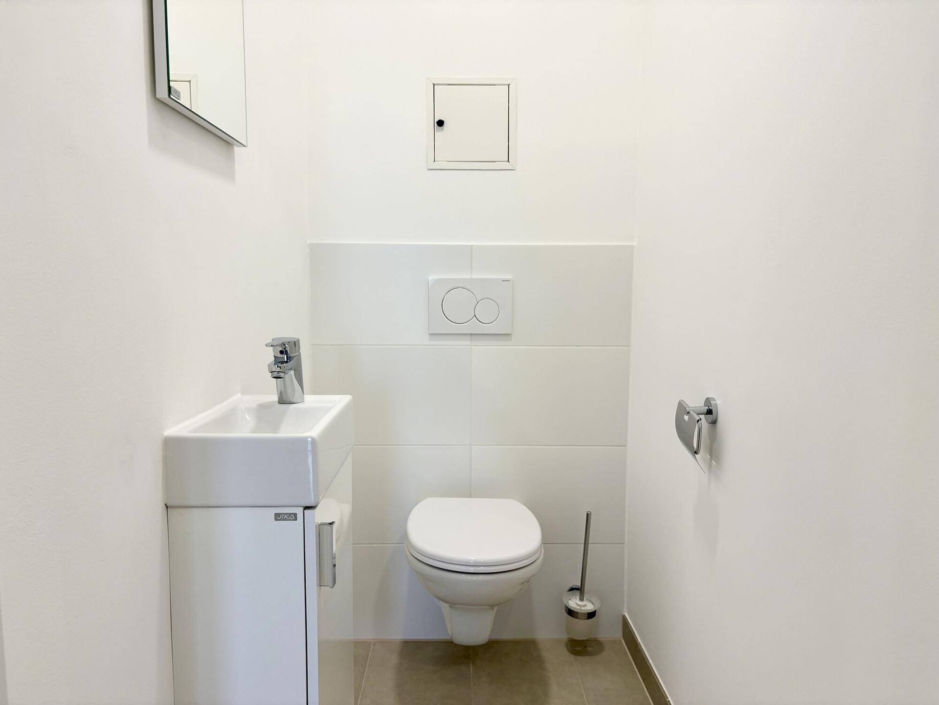Modernes Gäste-WC mit wandhängender Toilette und kleinem Handwaschbecken.