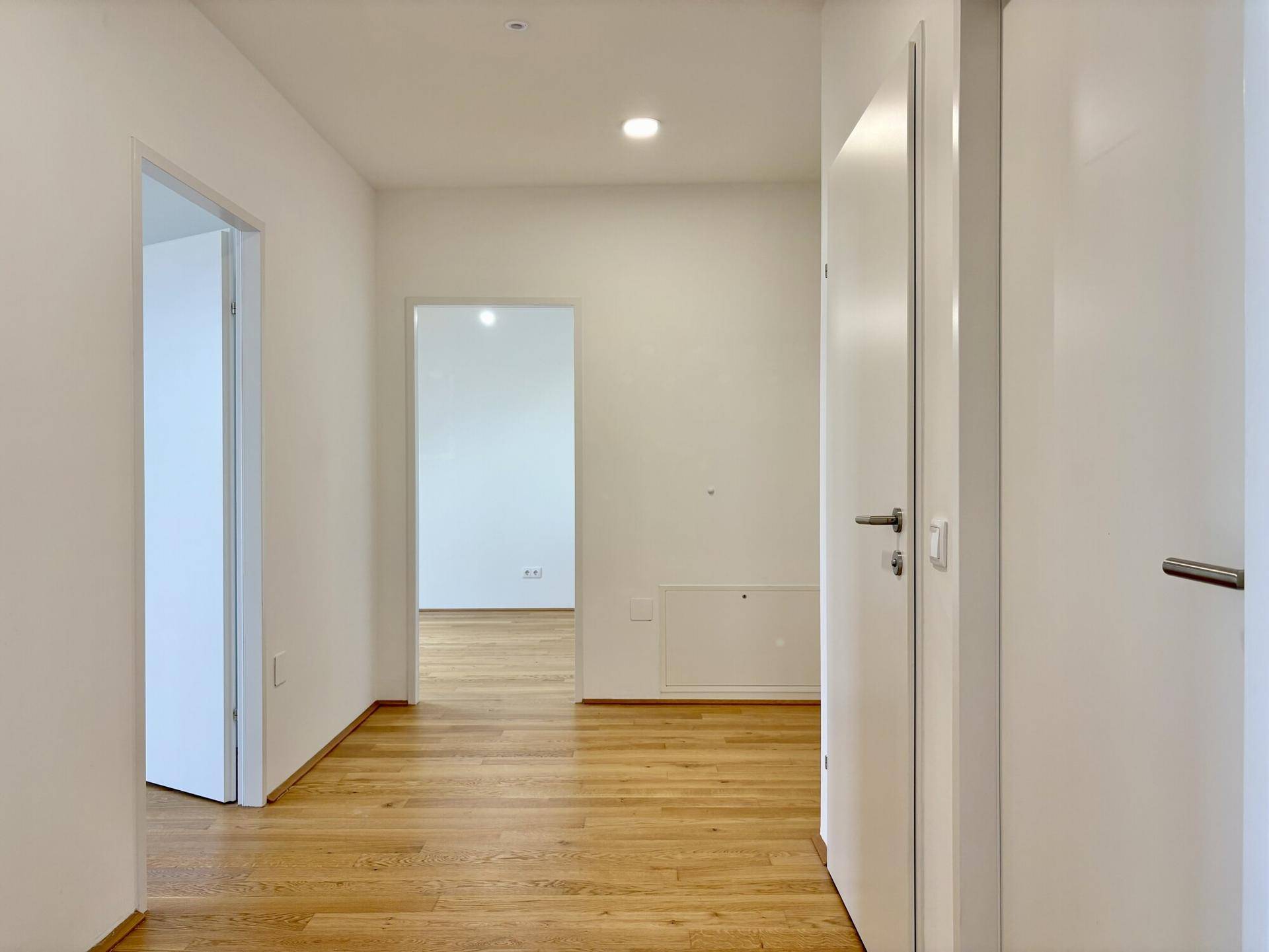 Geräumiger Flur mit Holzboden und Zugang zu verschiedenen Zimmern der Wohnung.