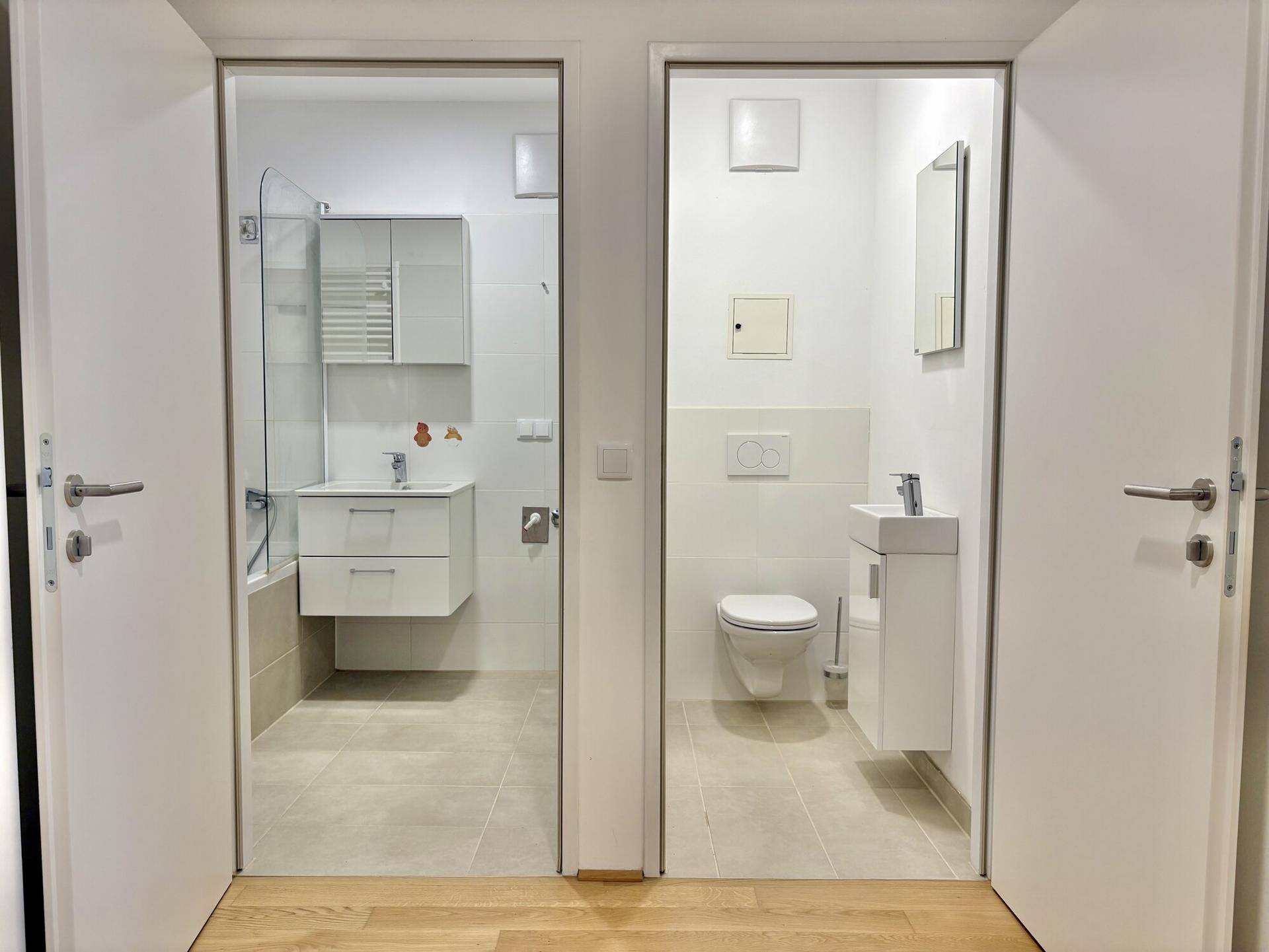 Flur mit Zugang zu einem modernen Badezimmer und einer separaten Gästetoilette.