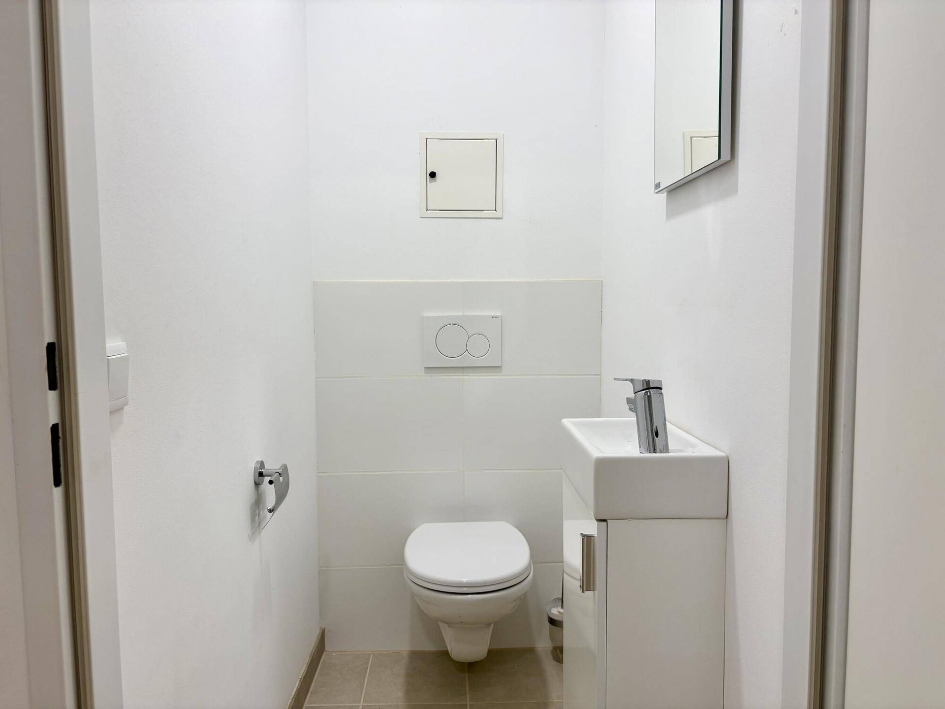 Separate Gästetoilette mit wandhängendem WC und kleinem Waschbecken, in modernem Design.