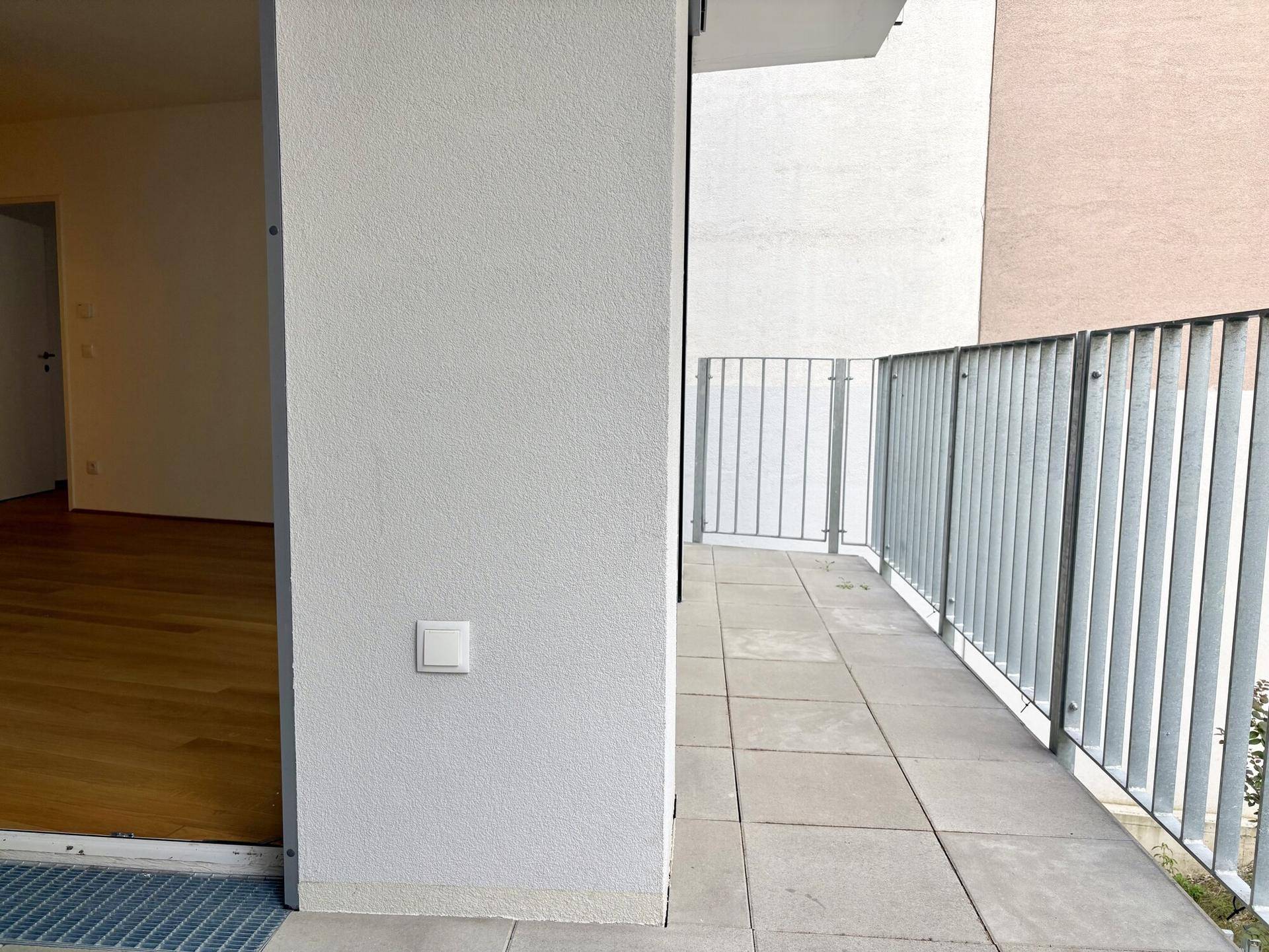 Geräumiger Balkon mit Fliesenboden und schlichtem Metallgeländer, ideal für entspannte Stunden im Freien.