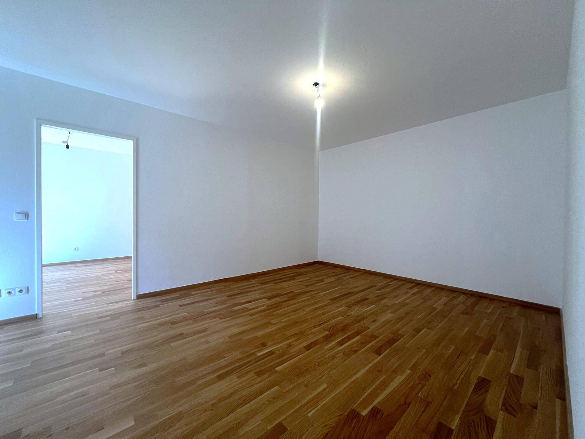 Heller Raum mit Holzboden und weiß gestrichenen Wänden, bereit zur individuellen Gestaltung.