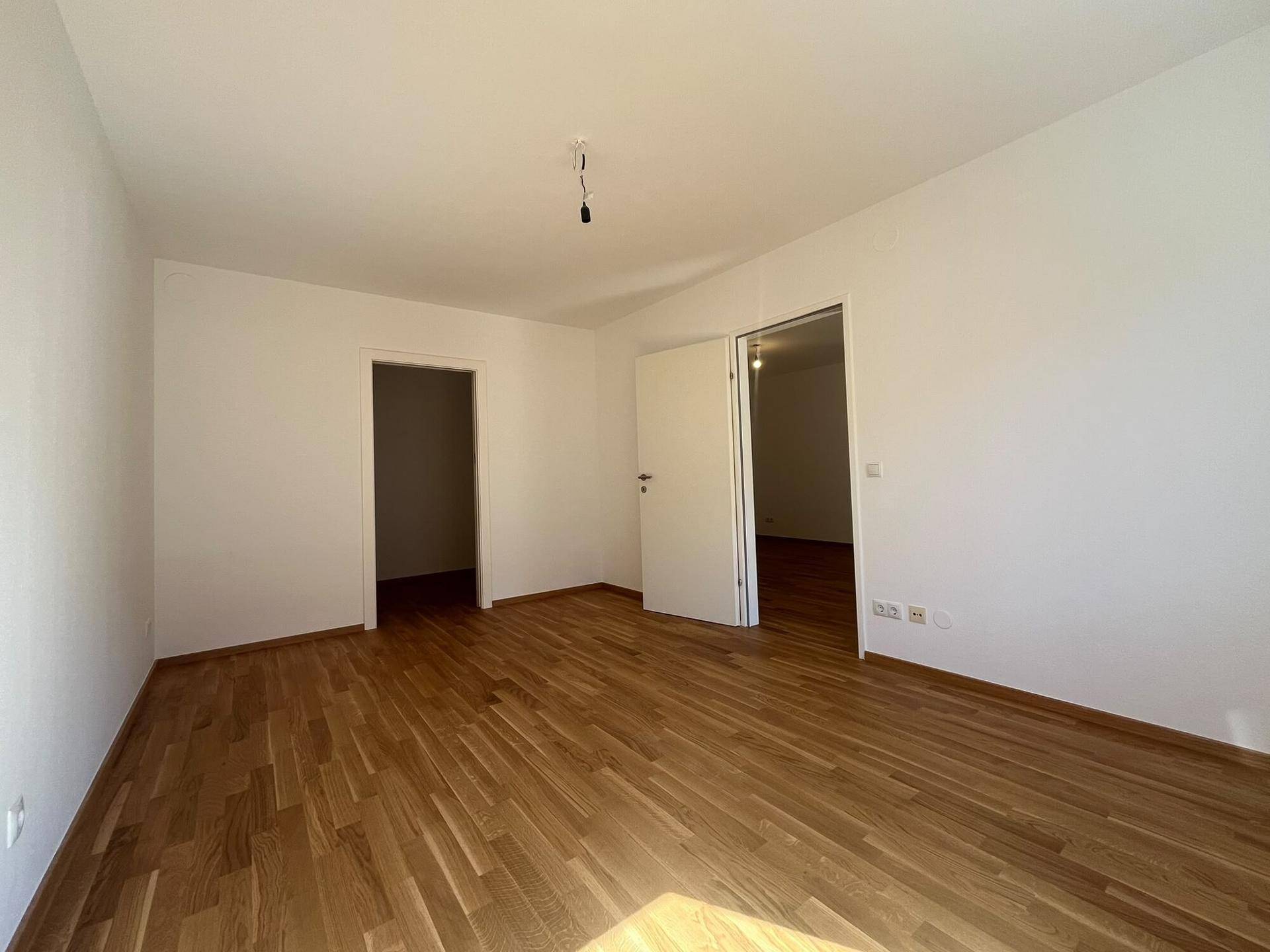 Geräumiger Raum mit Holzboden und zwei Türen, der vielseitig genutzt werden kann.