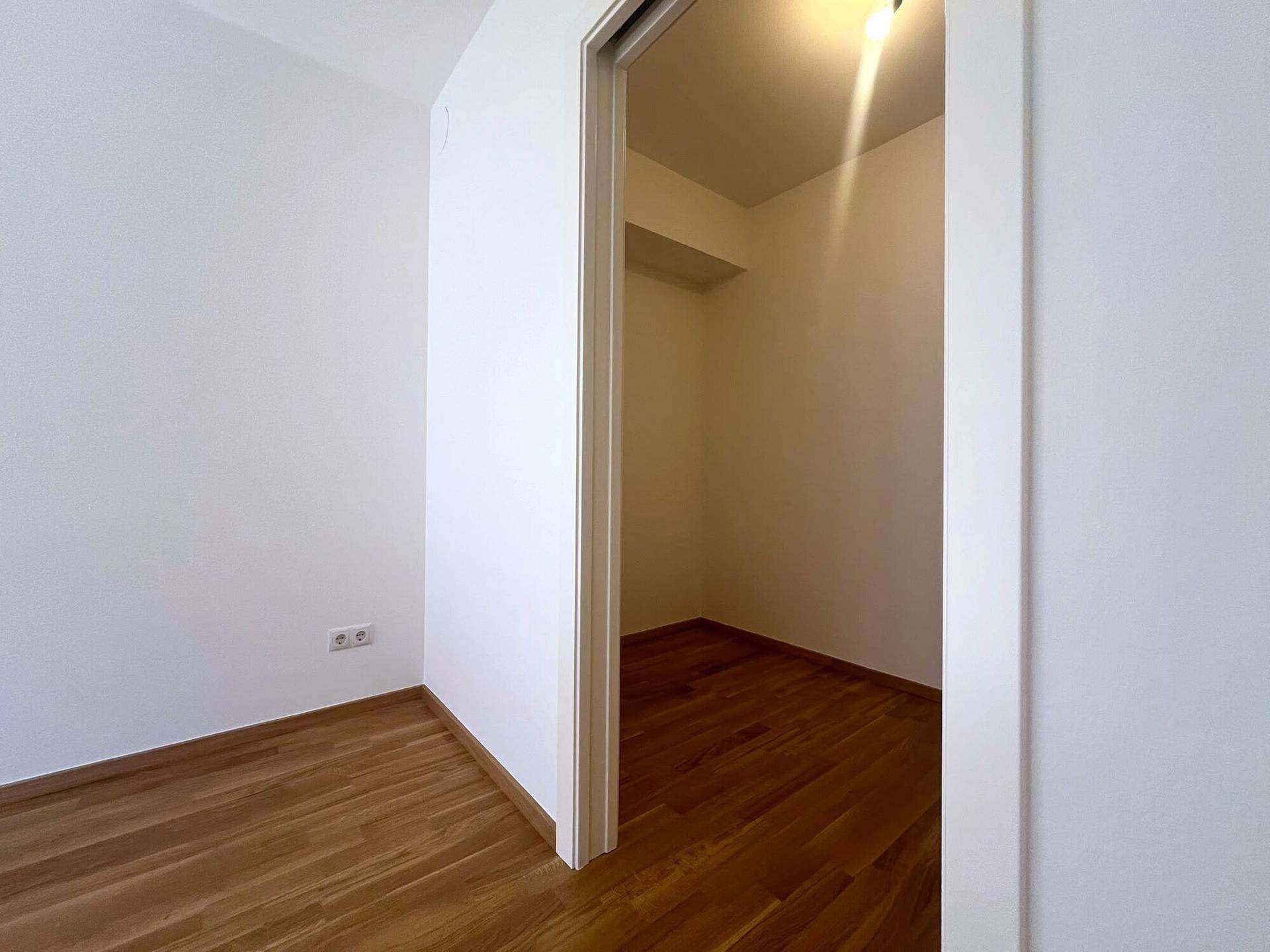 Kleiner Abstellraum oder begehbarer Kleiderschrank mit Holzboden, ideal für zusätzlichen Stauraum.