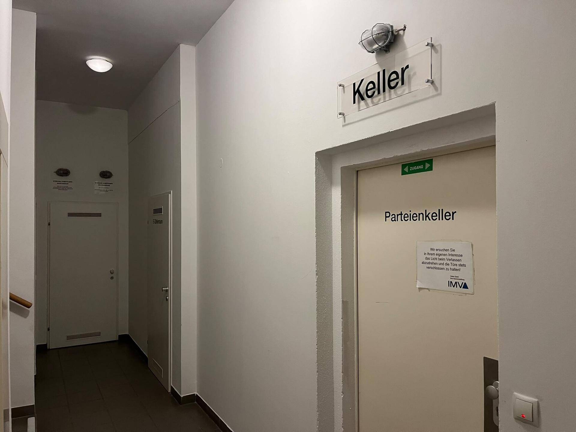 Flur im Gebäude mit Hinweisschildern zu den Kellerabteilen und dem allgemeinen Kellerbereich.