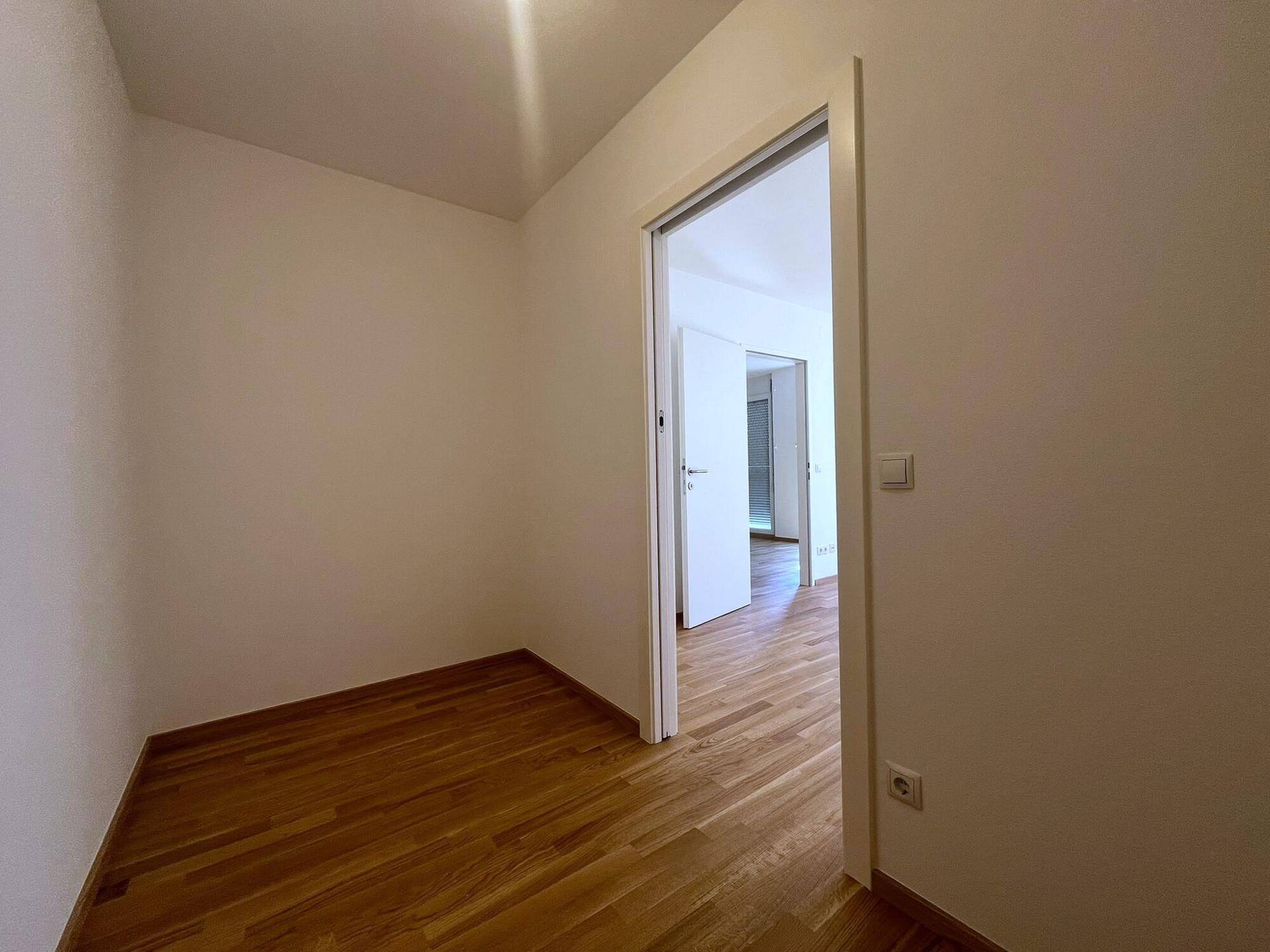 Weiterer Blick in den kleinen Raum mit Holzboden, der als Abstellkammer dienen könnte.