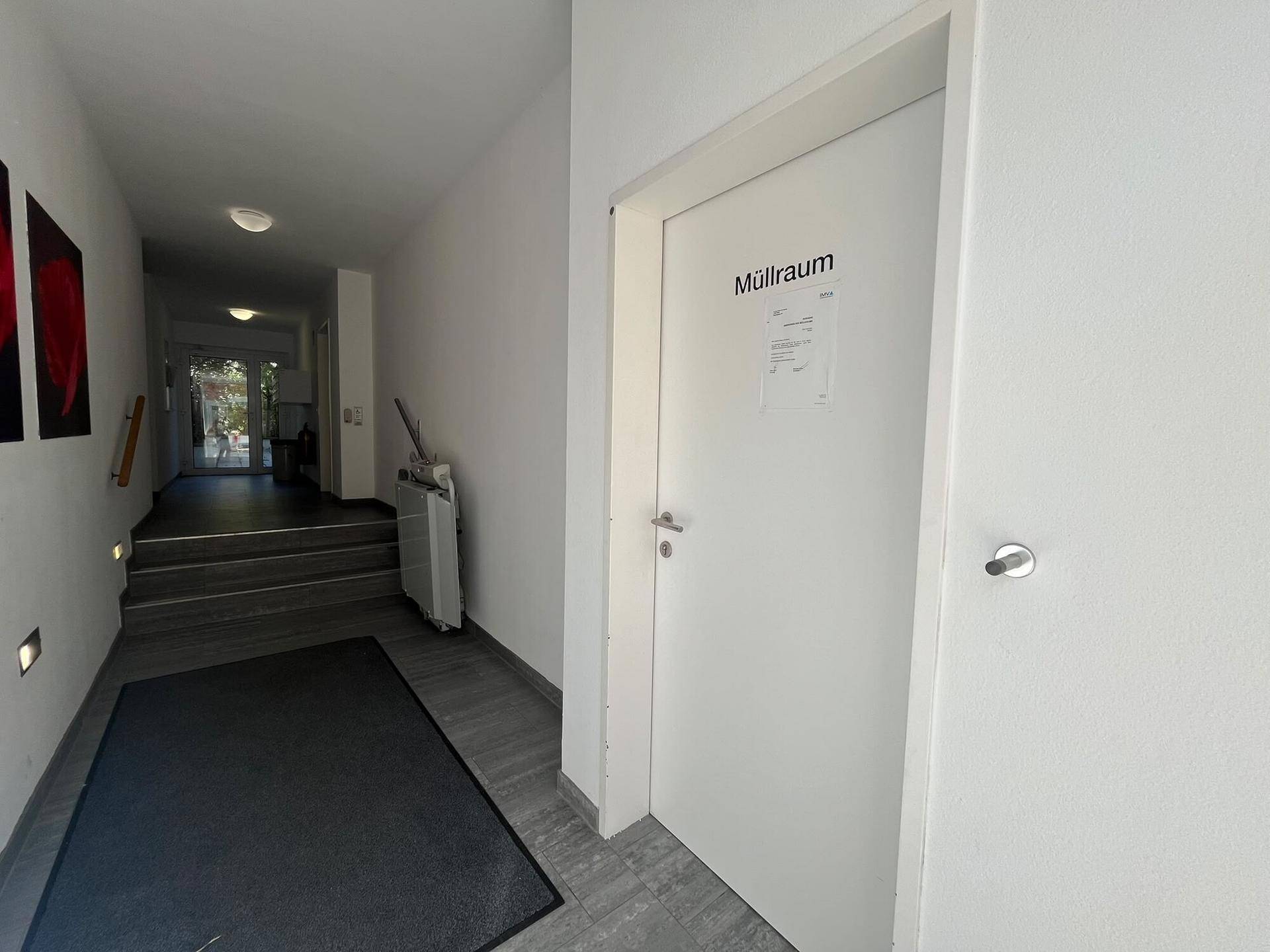 Heller Flur im Gebäude mit Zugang zum Müllraum und weiteren Gemeinschaftsbereichen.
