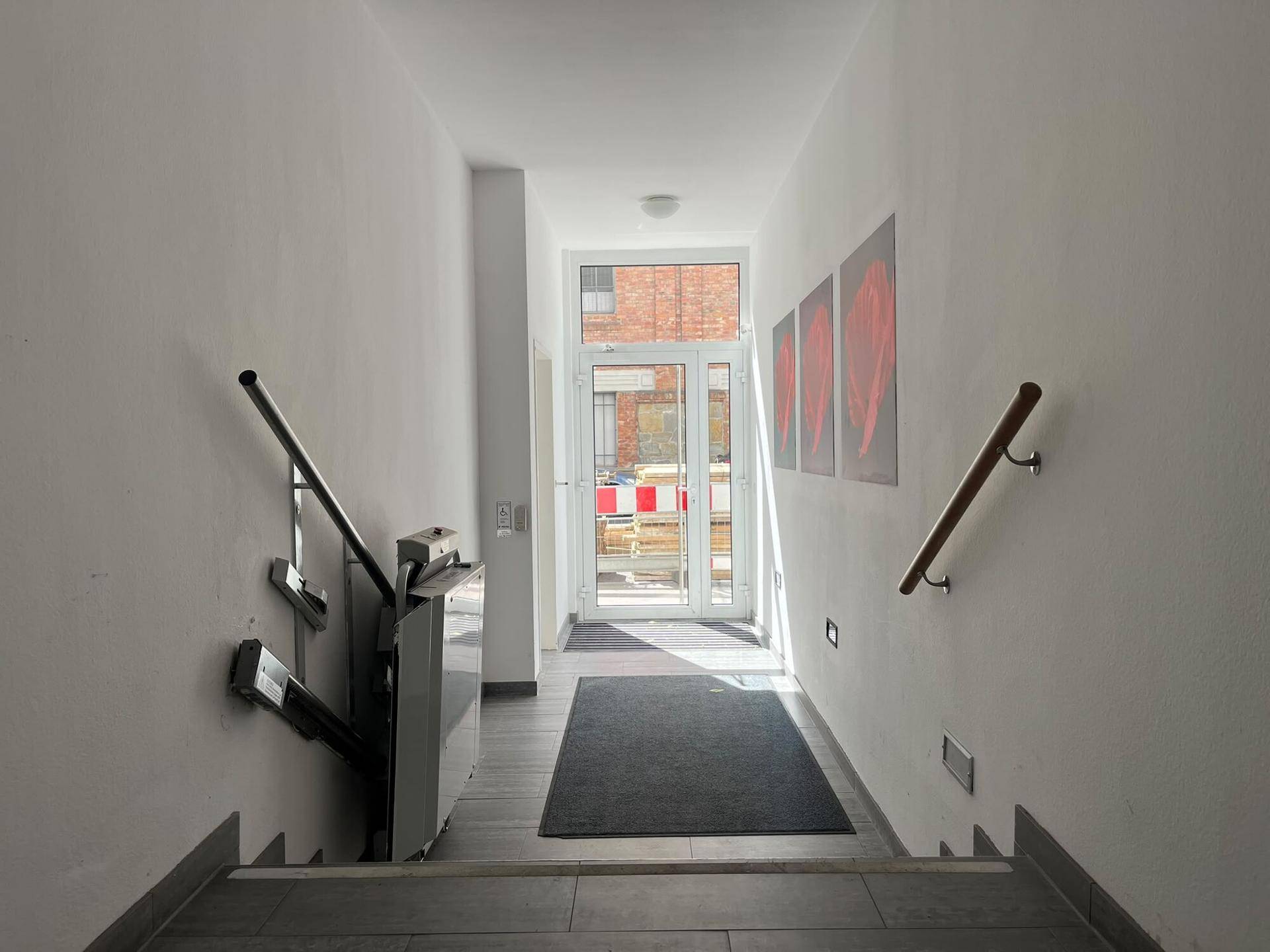 Treppenhaus mit Treppenlift und Zugang zum Eingangsbereich des Gebäudes.