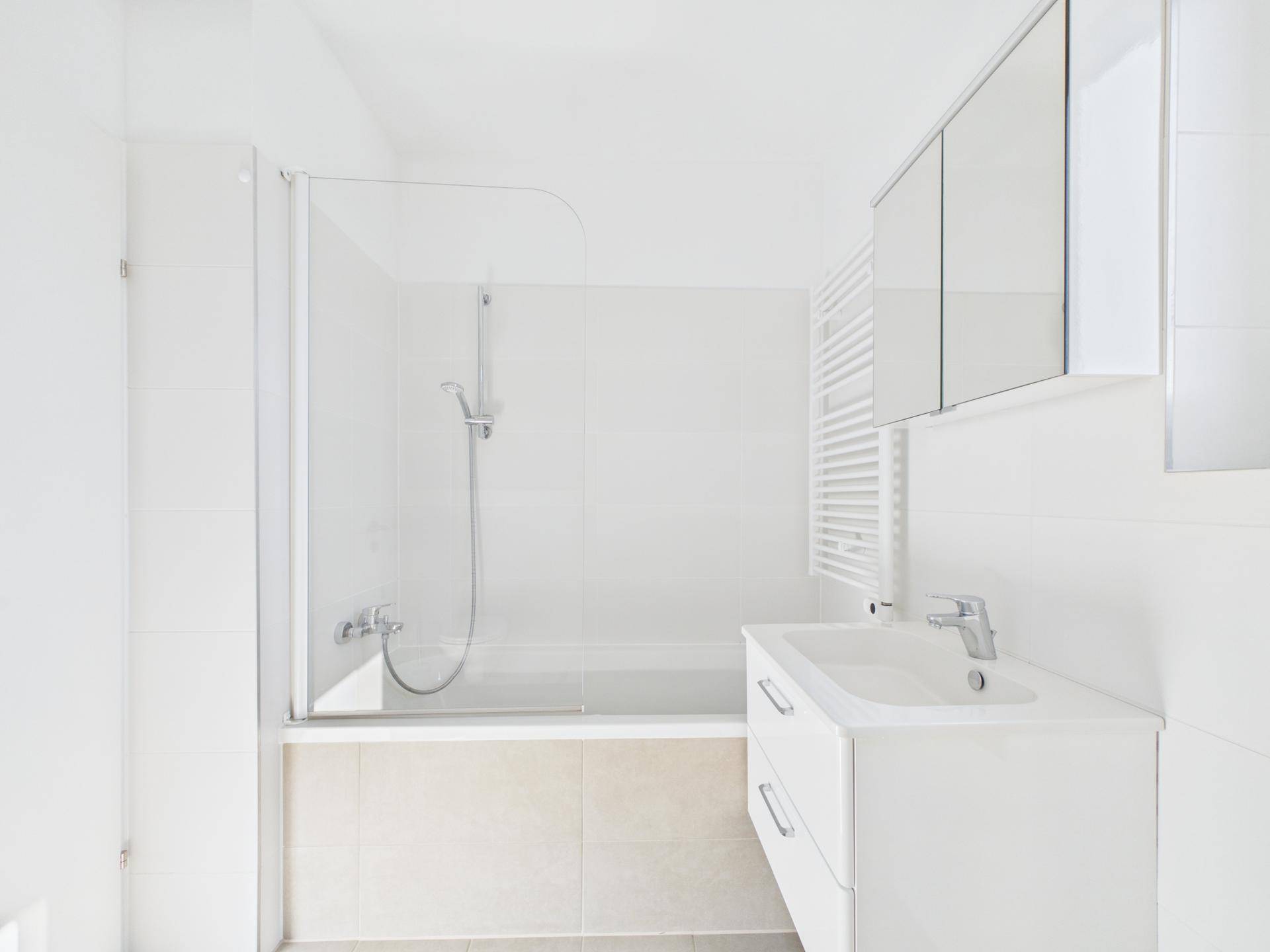 Modernes Badezimmer mit Badewanne, Duschfunktion, Waschbecken und beheiztem Handtuchhalter.